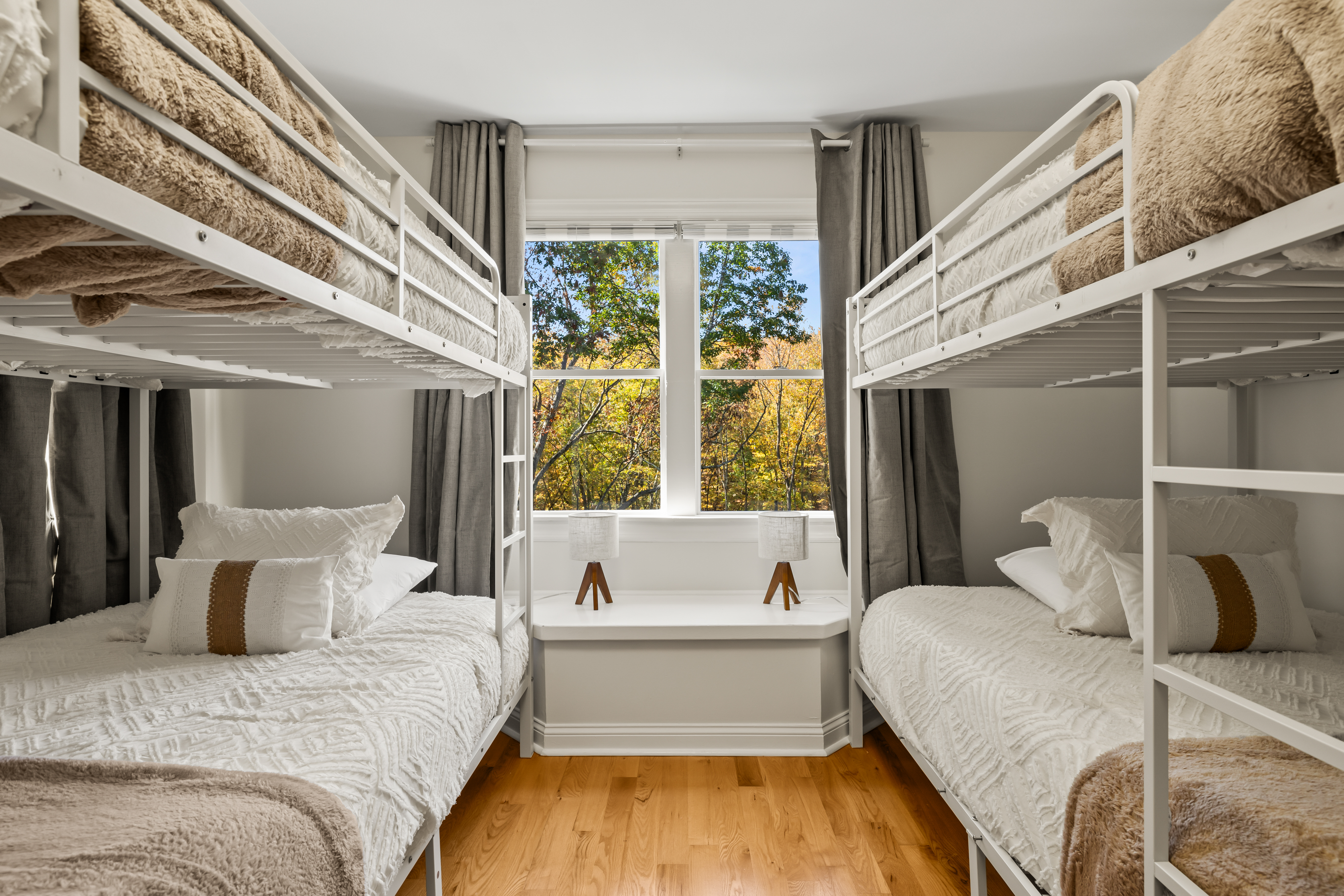 Bright bunk room with cozy beds, tree views, and space for the whole group
