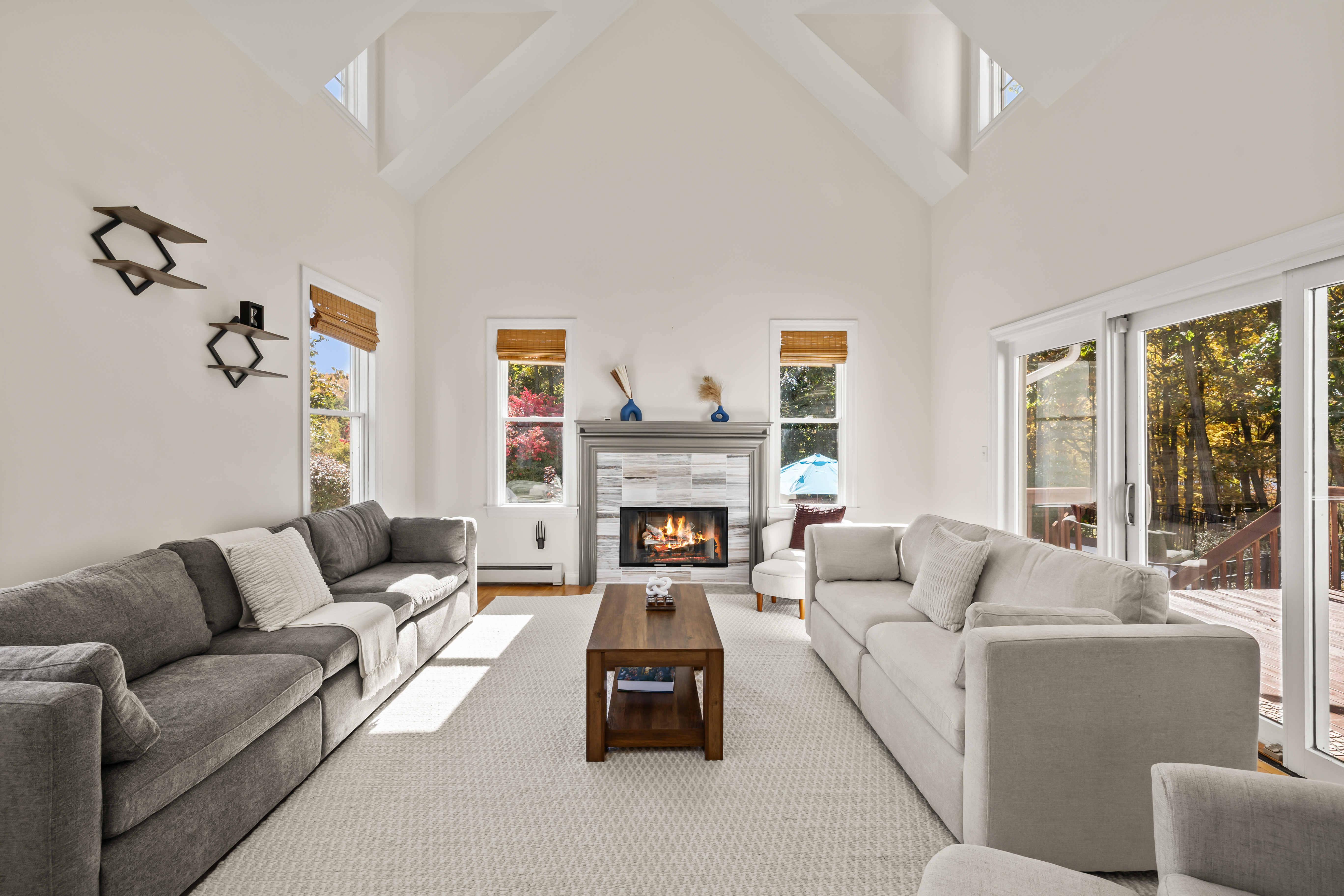 Sun-filled vaulted living room with fireplace and deck access