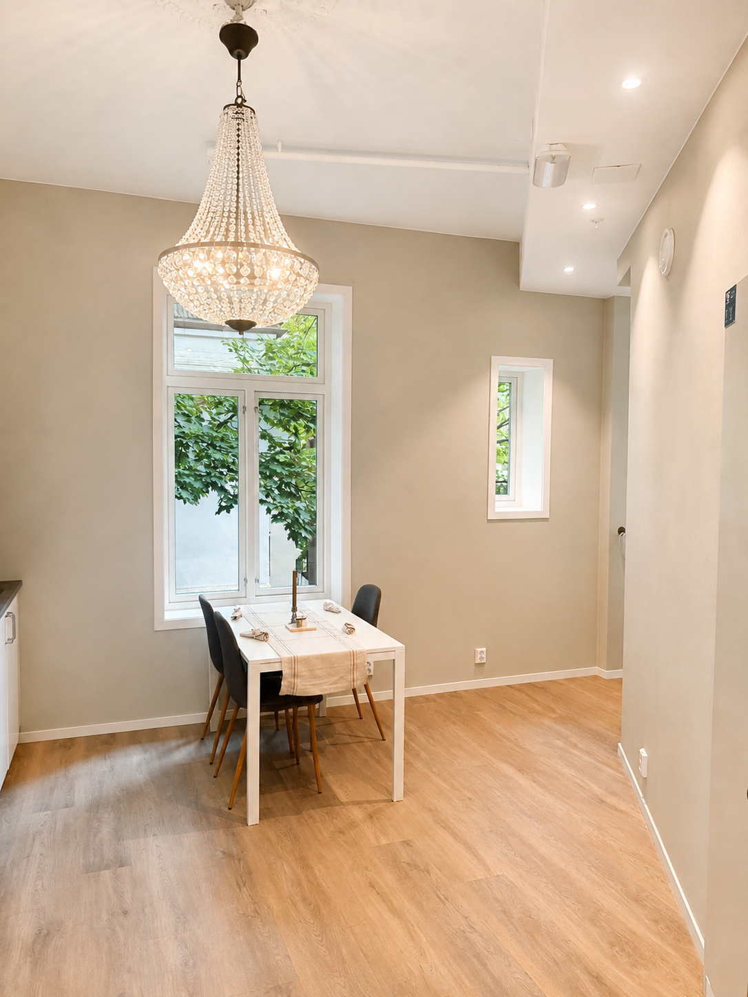 Elegant dining nook with chandelier, natural light, and leafy window views