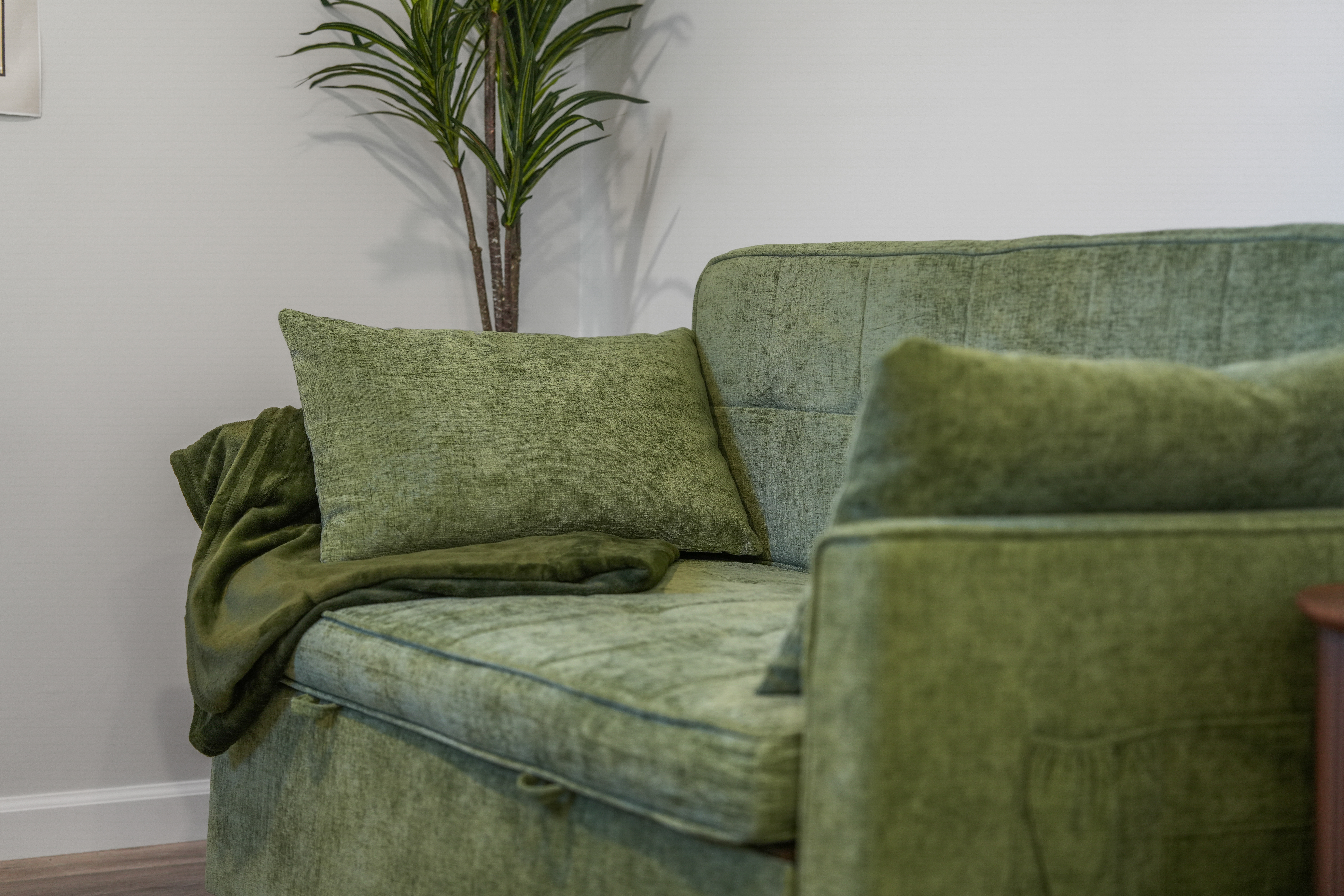 Cozy green sofa with soft throws and a stylish, calming modern touch