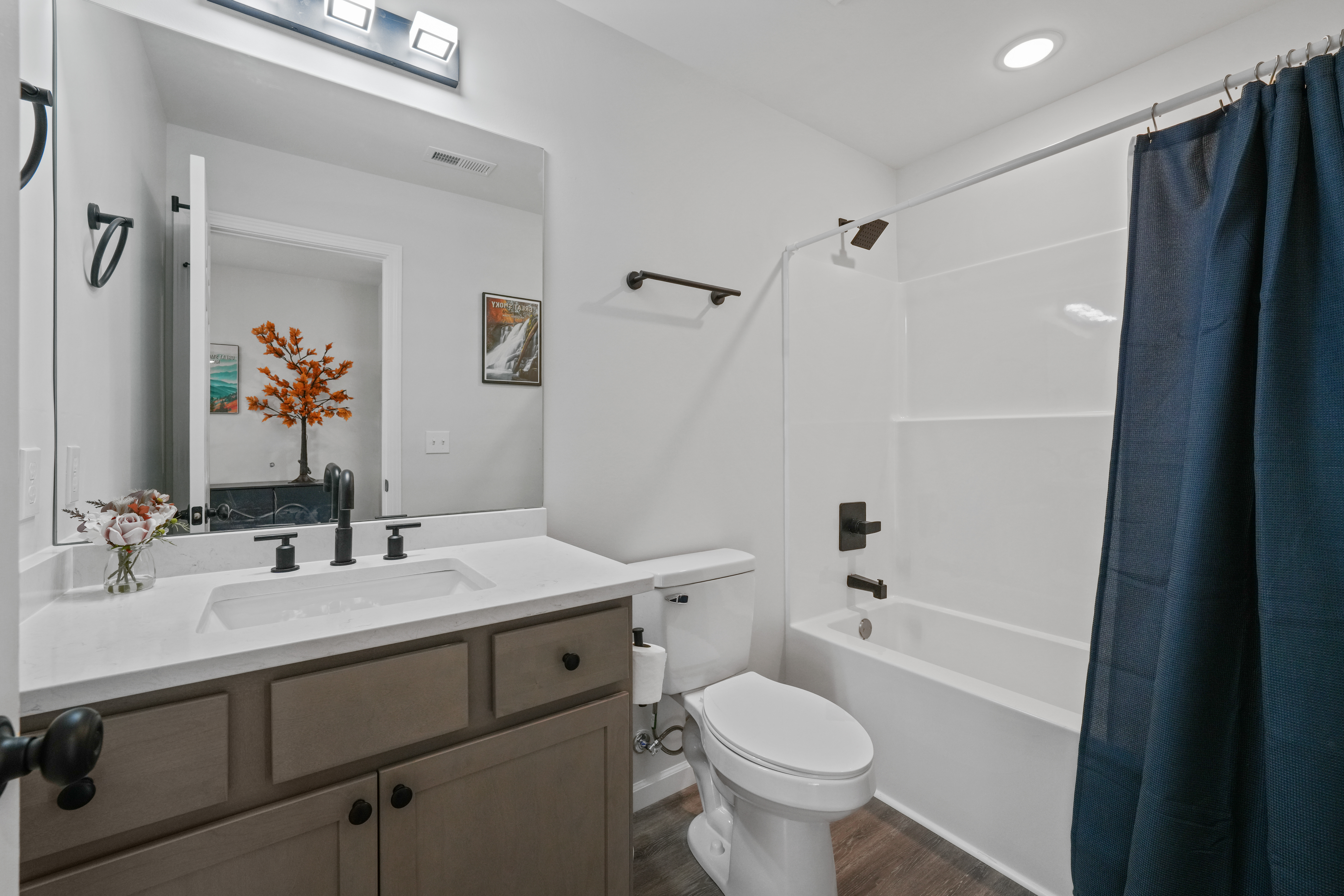 Bright modern bathroom with tub-shower combo and stylish dark fixtures