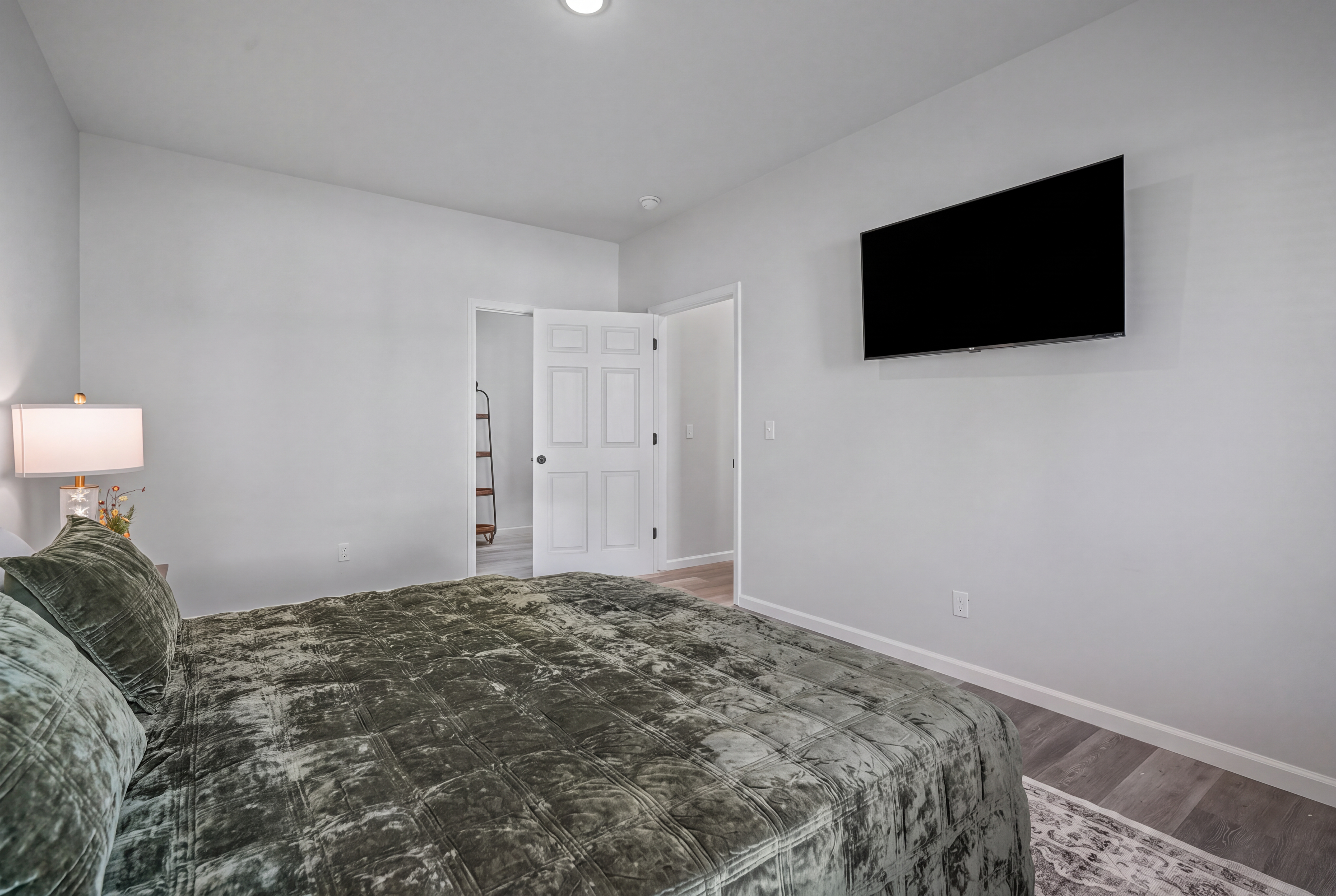 Bright, cozy bedroom with plush bedding and wall-mounted TV