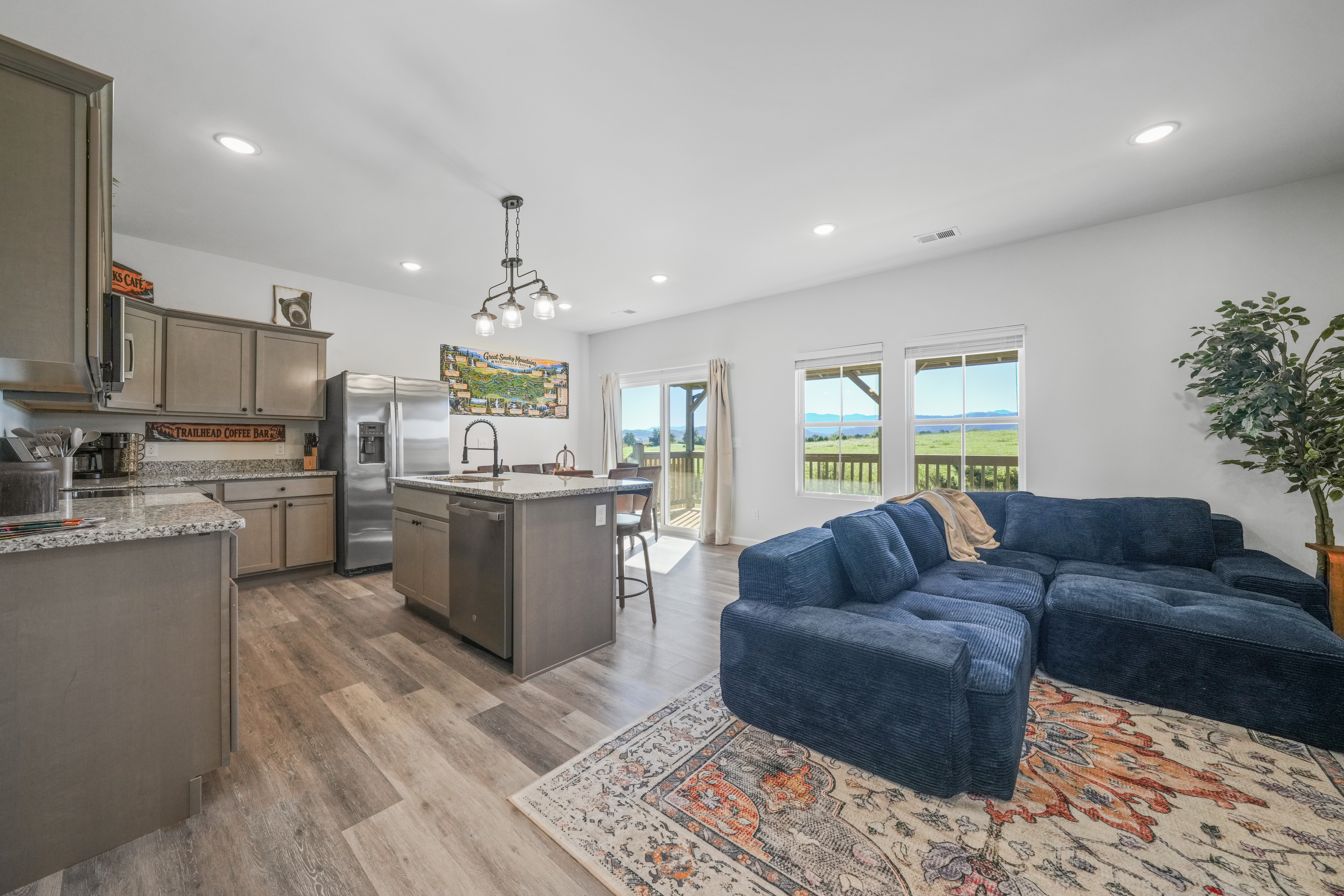 Bright open living space with scenic views, deck access, and a cozy sectional