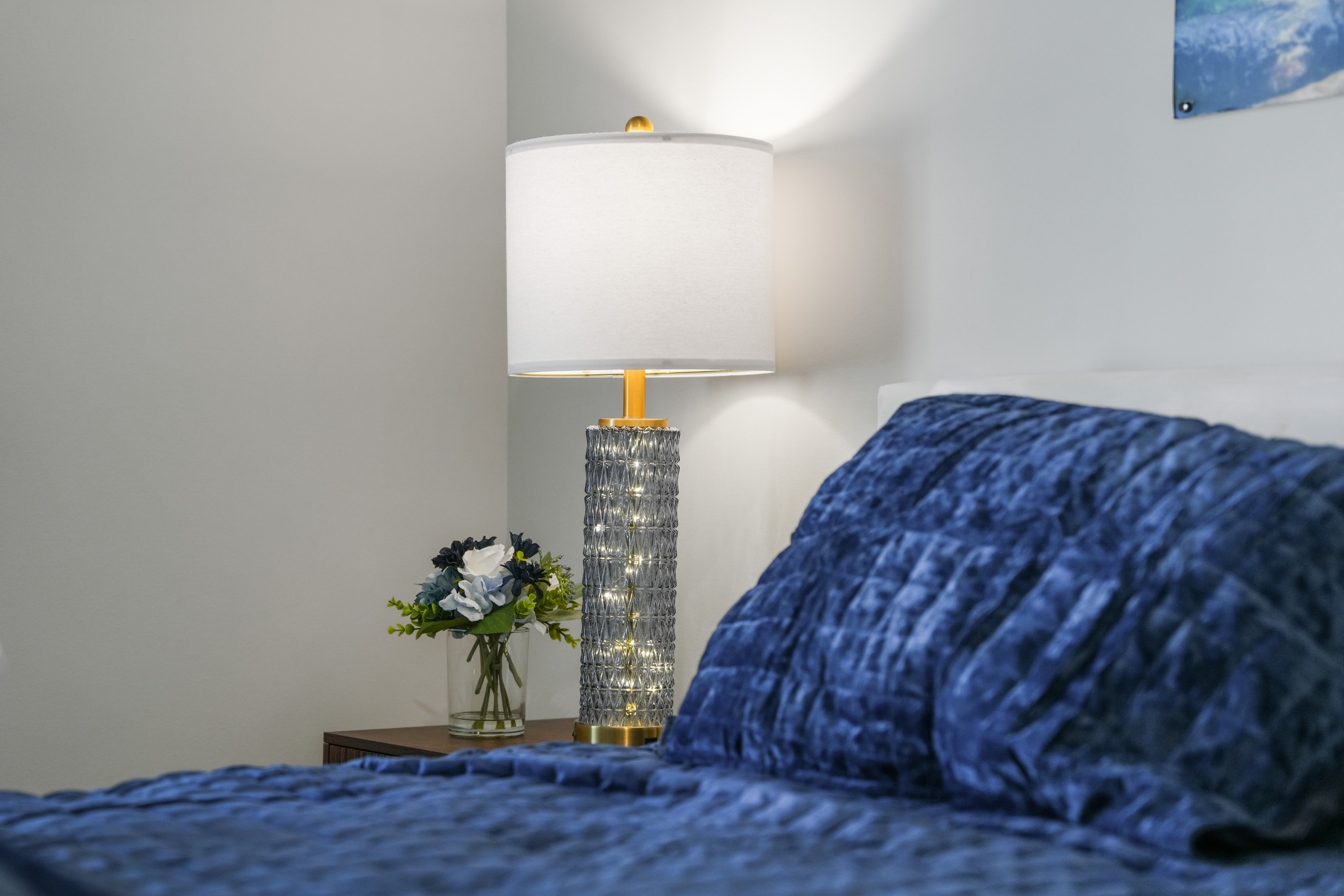 Cozy bedroom with plush blue bedding and warm bedside lighting