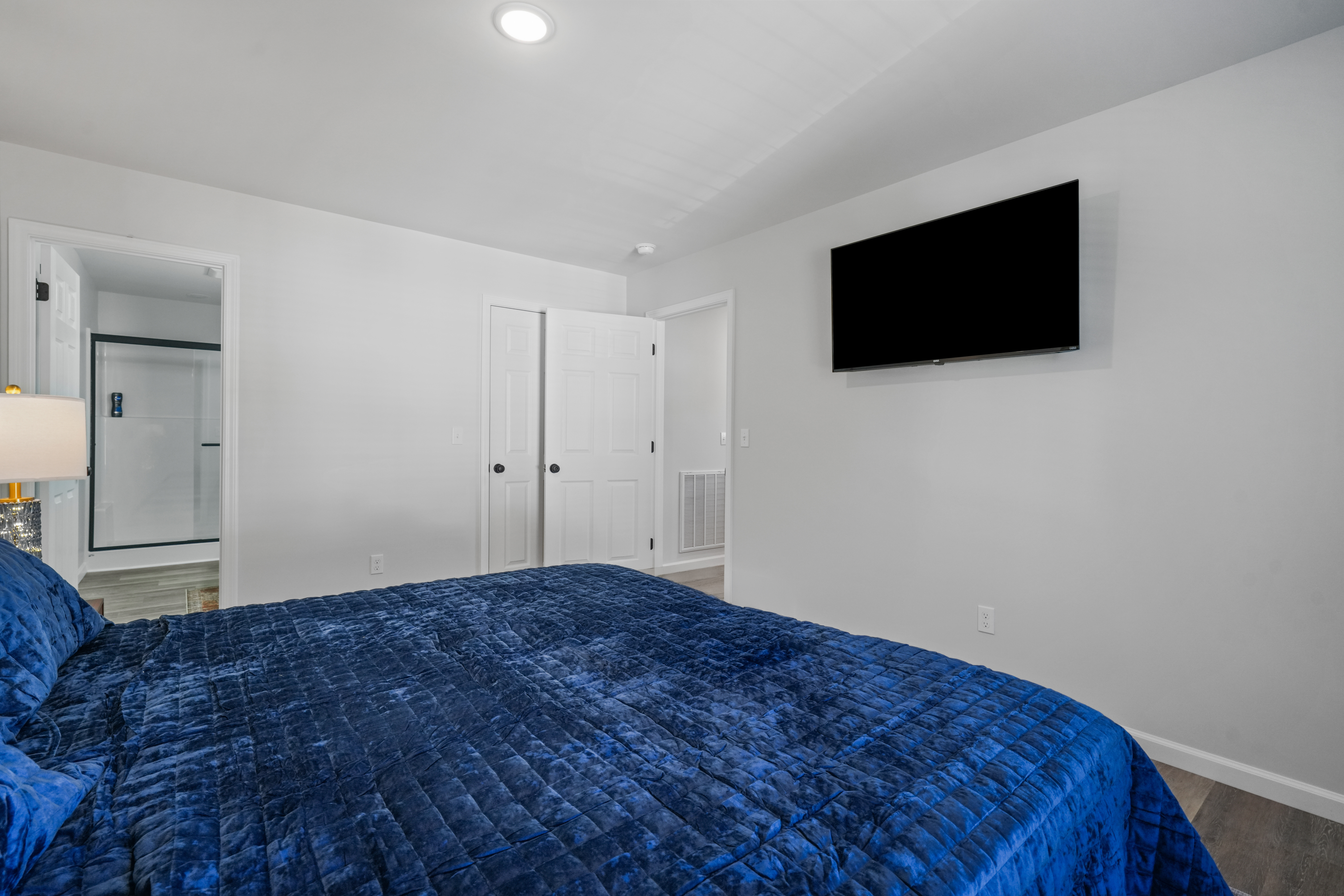 Bright bedroom with plush king bed, ensuite bath, and wall-mounted TV
