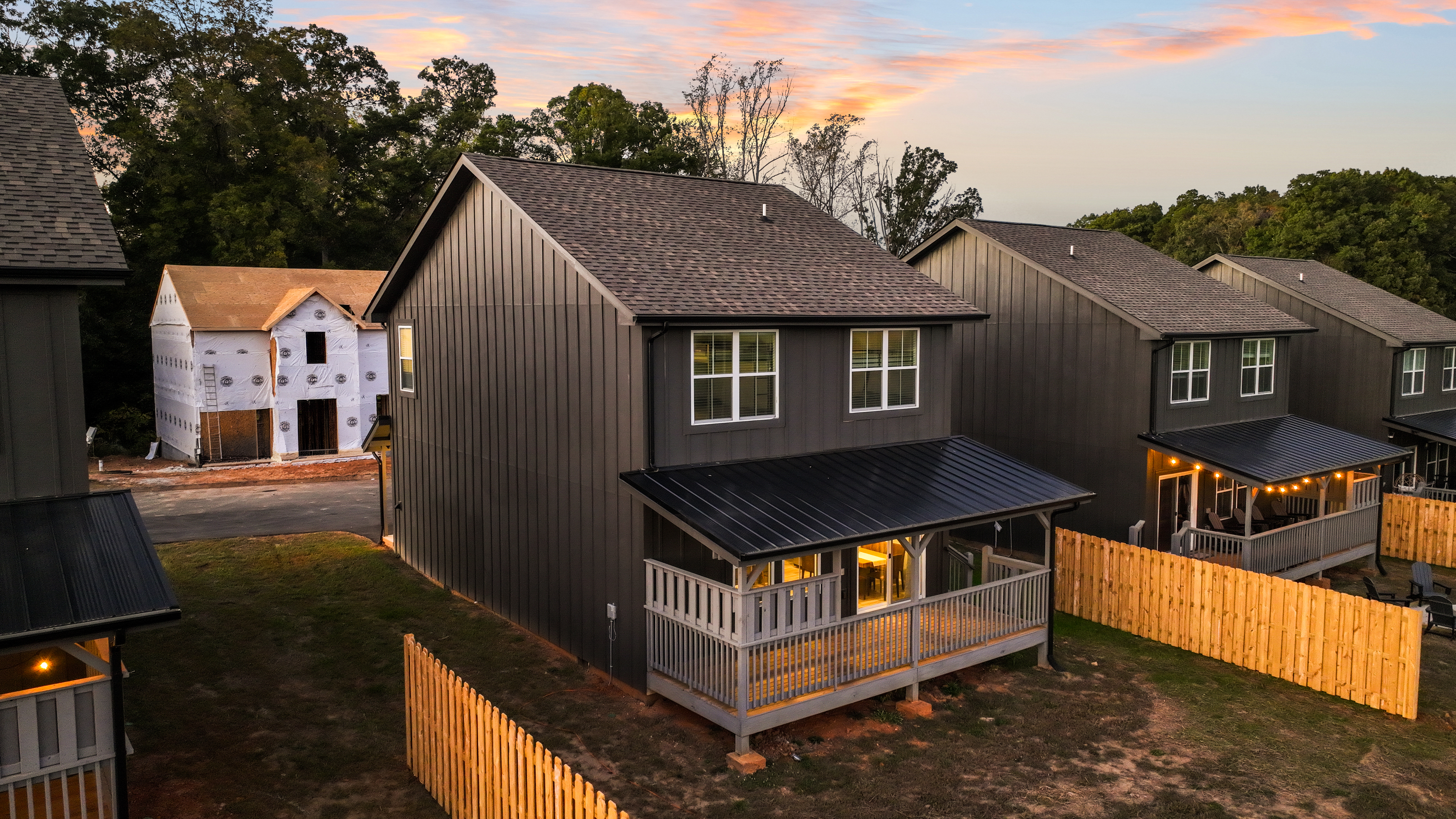 Modern home with covered porch, warm lighting, and private fenced yard