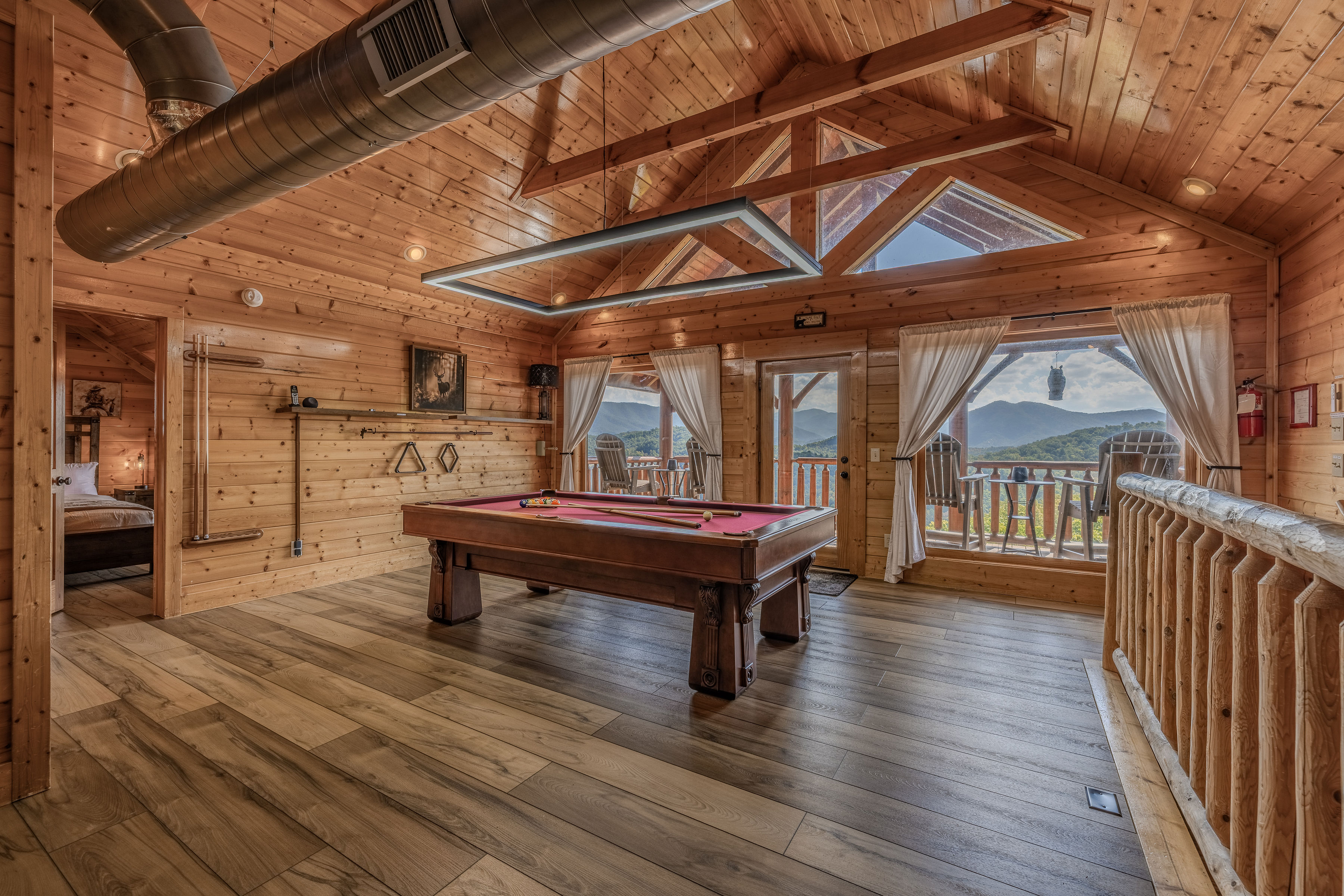 Rustic upper game room with pool table and stunning mountain-view balcony