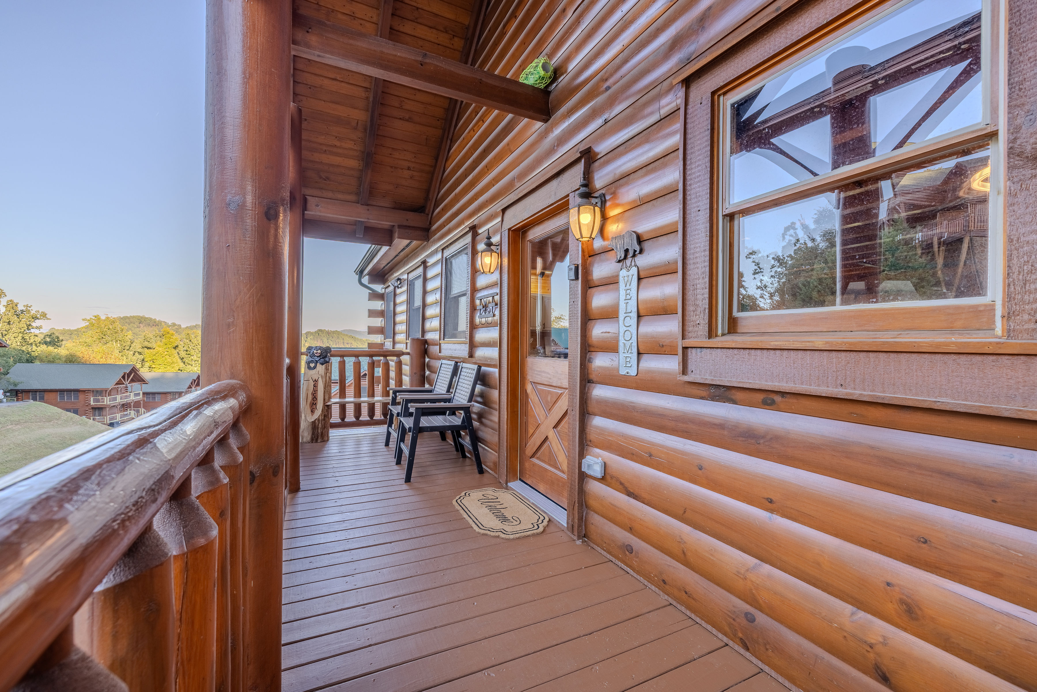 Covered log cabin porch with cozy seating and peaceful wooded views