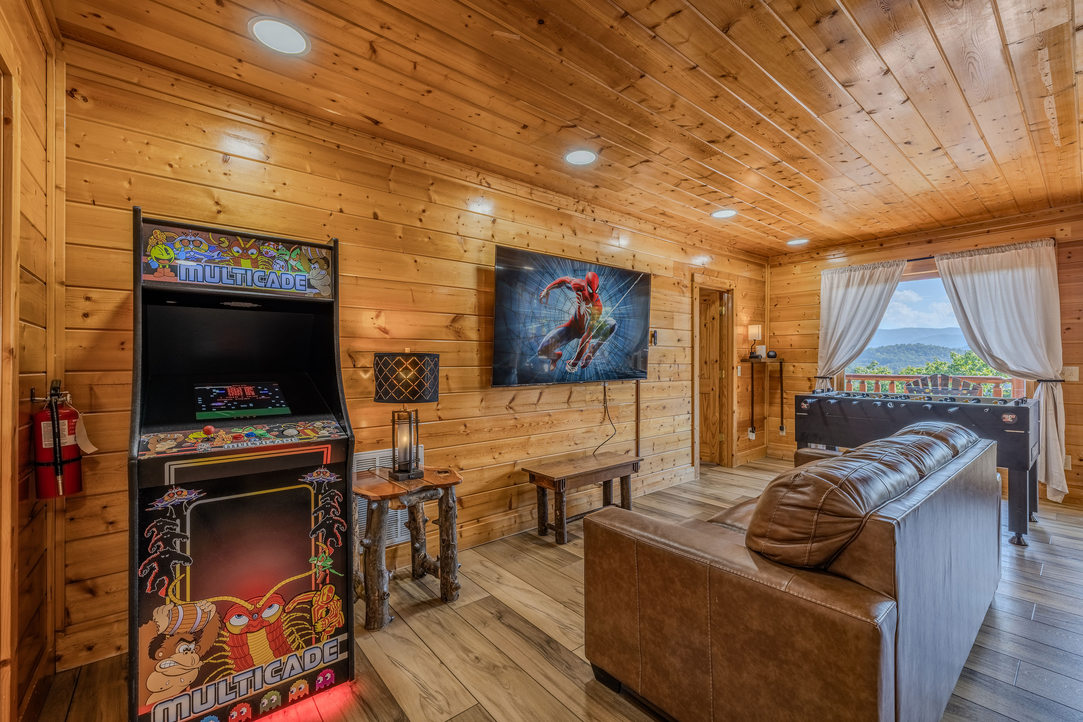 Cozy game room with arcade, foosball, TV, and mountain-view windows