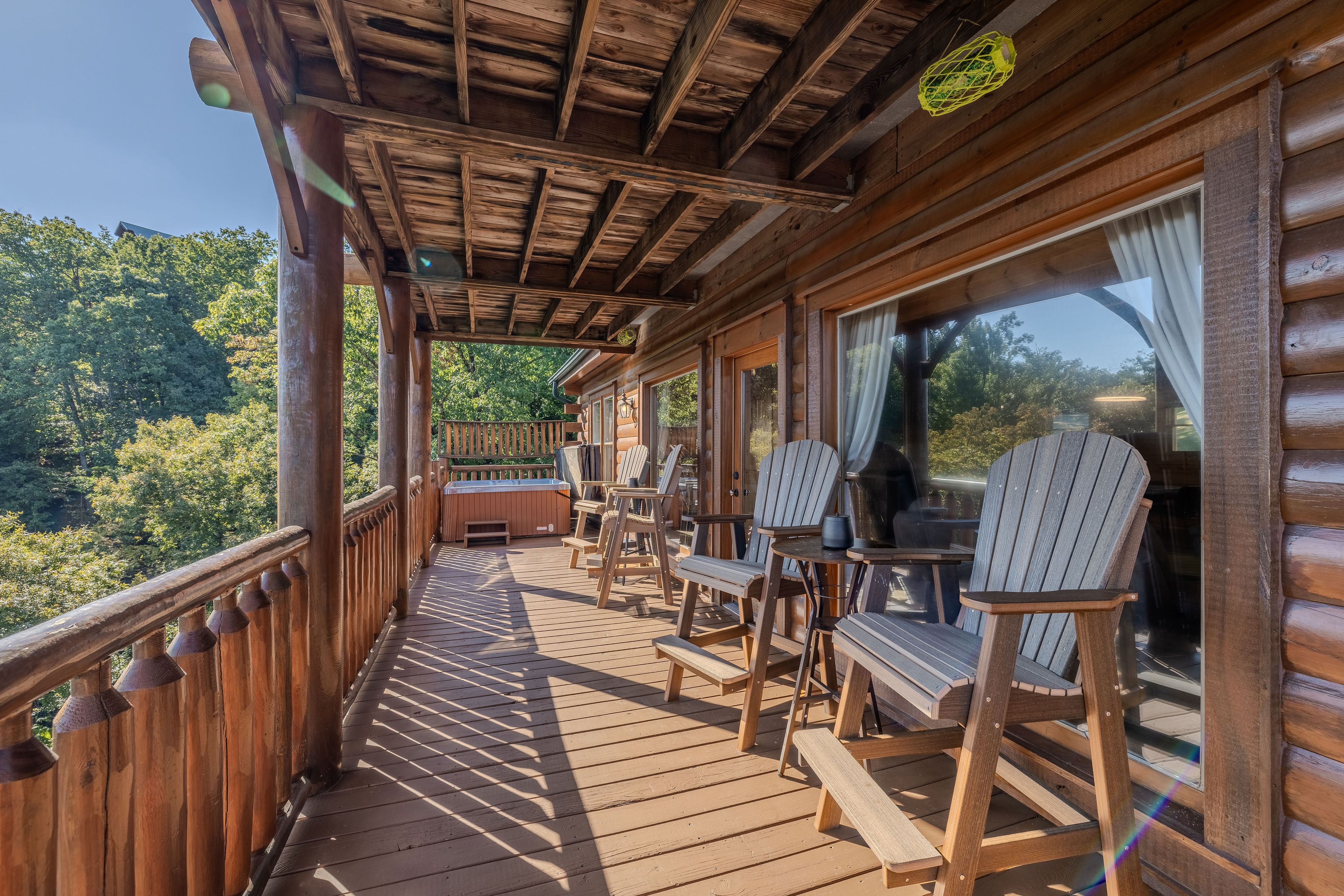 Covered cabin deck with poly wood pub chairs, forest mountain views, and a private hot tub, middle deck