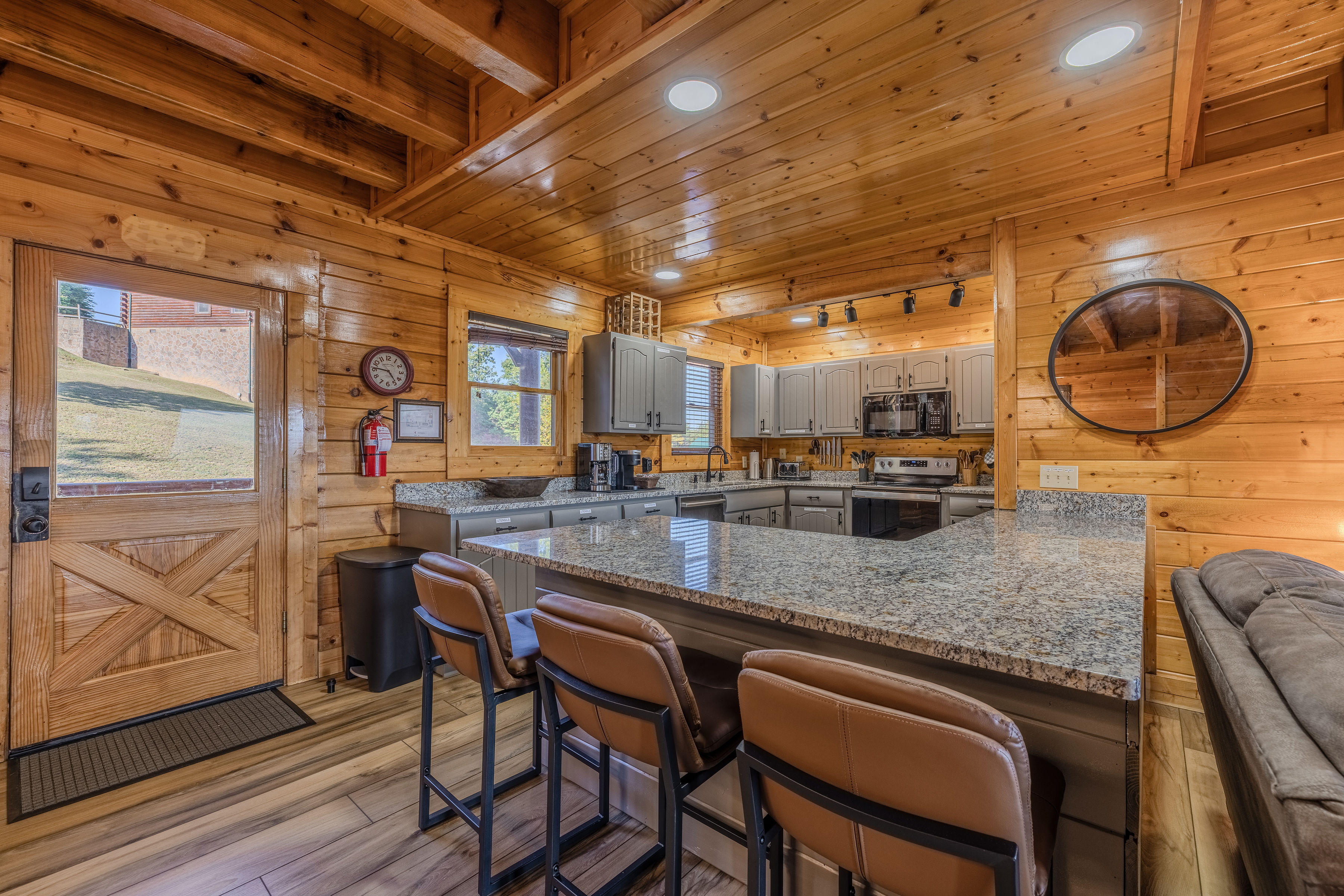 Cozy wood-lined kitchen with granite bar seating and modern appliances