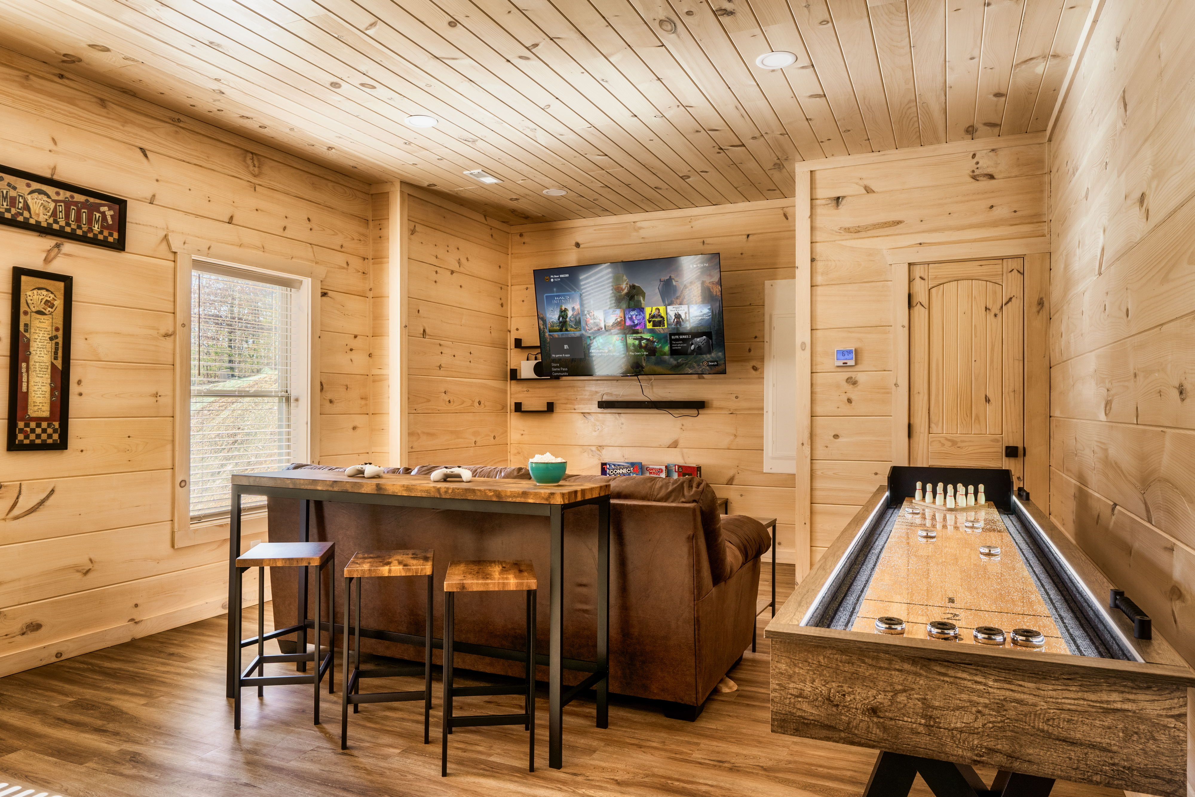 Cozy game room with smart TV, shuffleboard, and rustic cabin charm