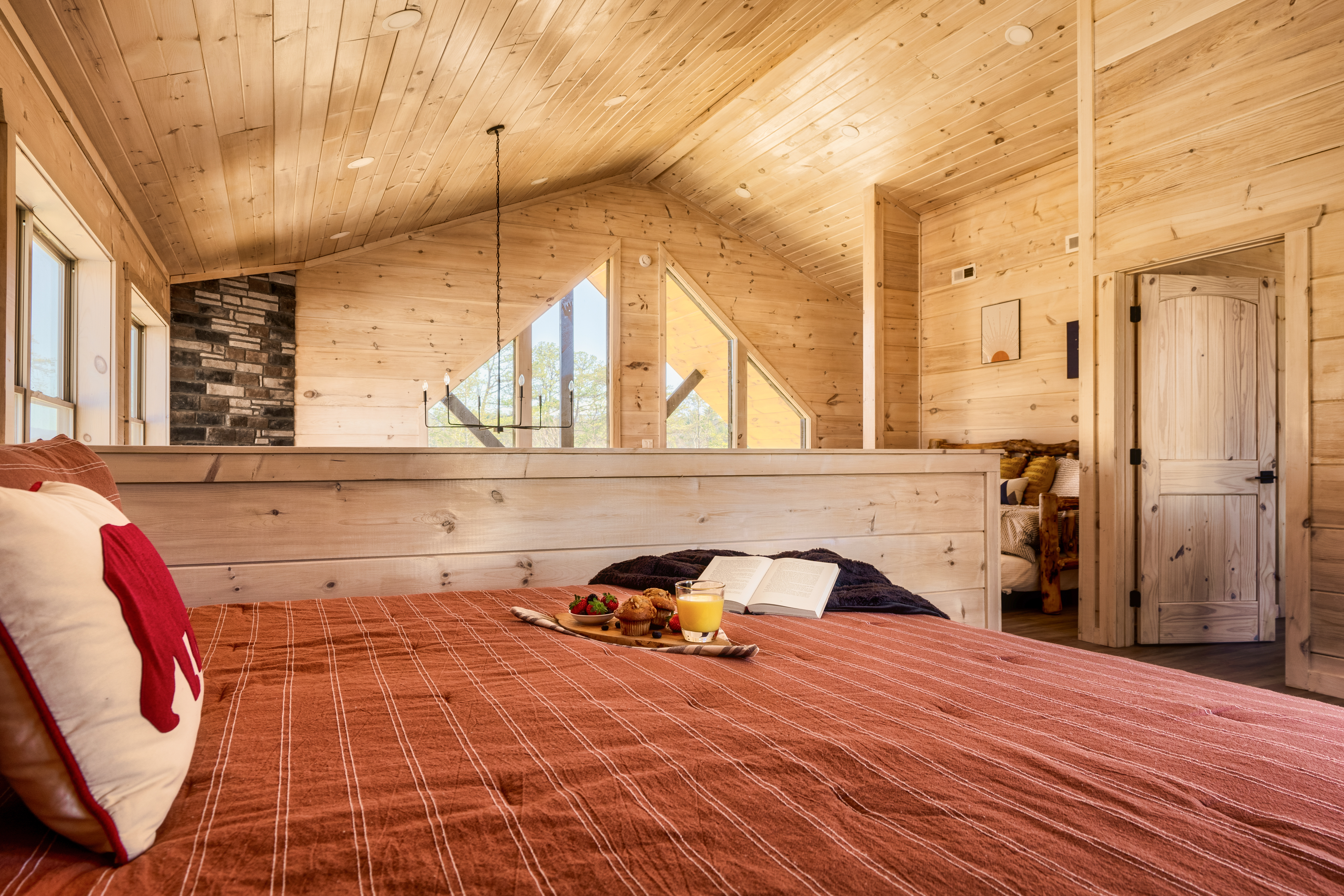 Cozy wood-lined loft bedroom with natural light and rustic charm