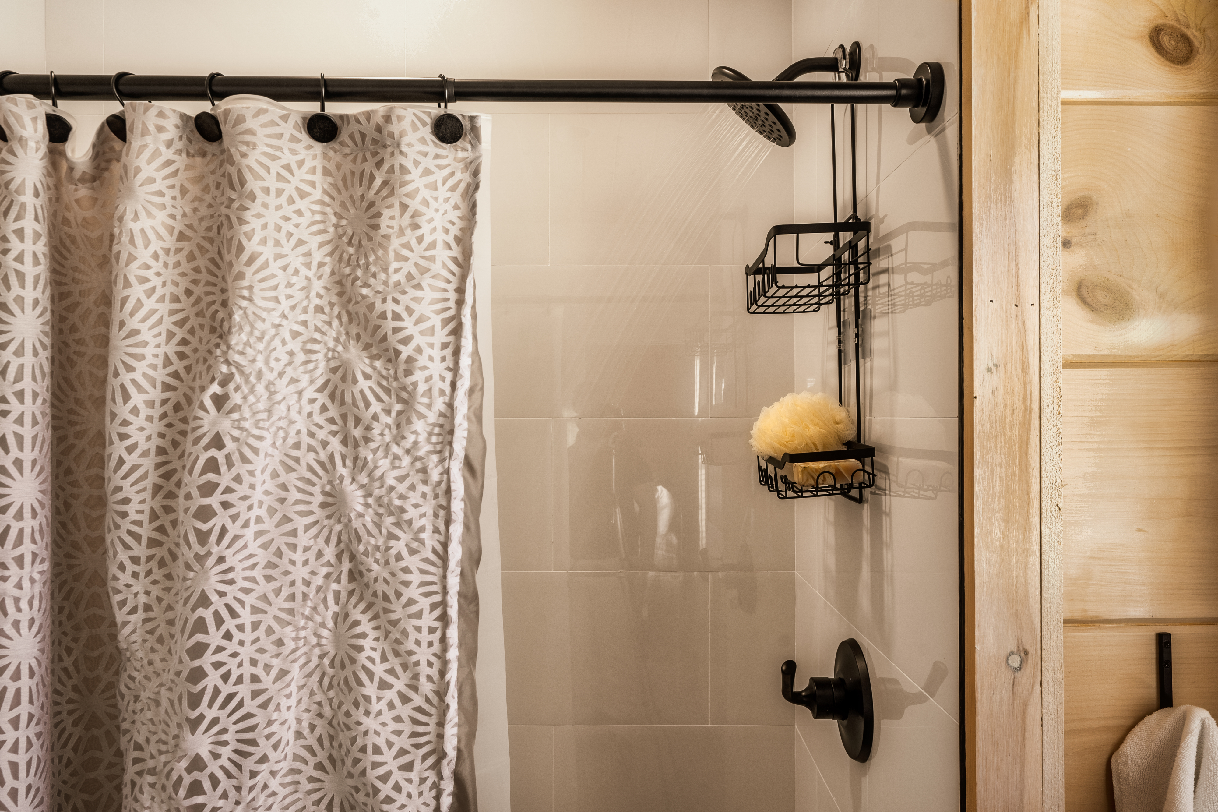 Modern tiled shower with black fixtures and warm rustic wood accents
