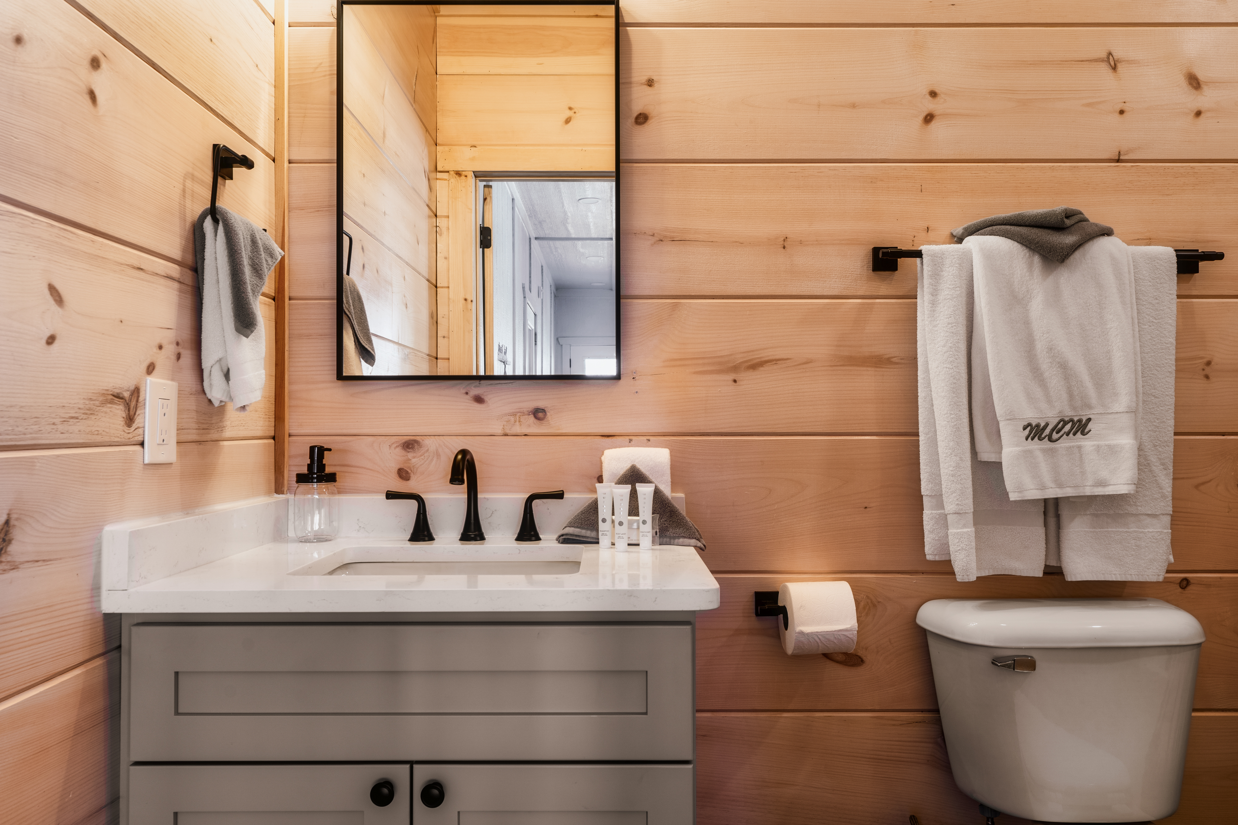 Modern rustic bathroom with warm wood walls and stylish black fixtures