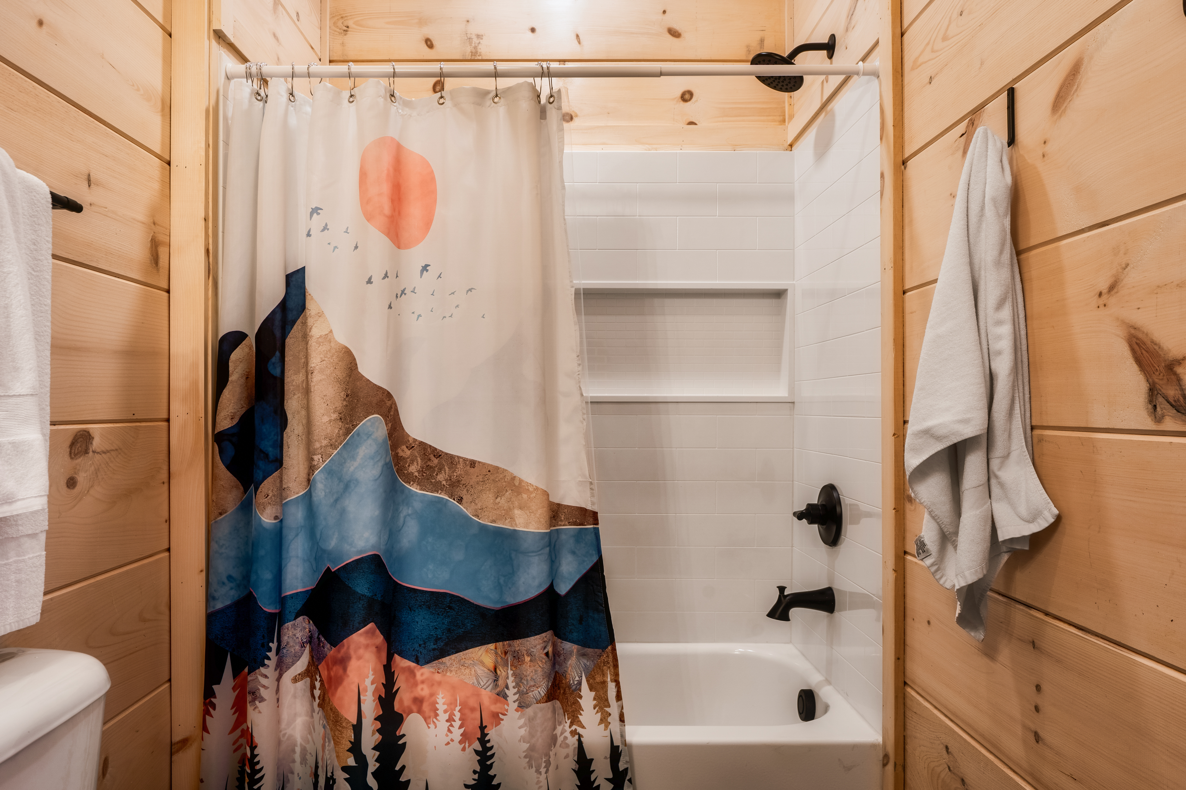 Rustic-modern bath with mountain-themed shower curtain and clean finishes