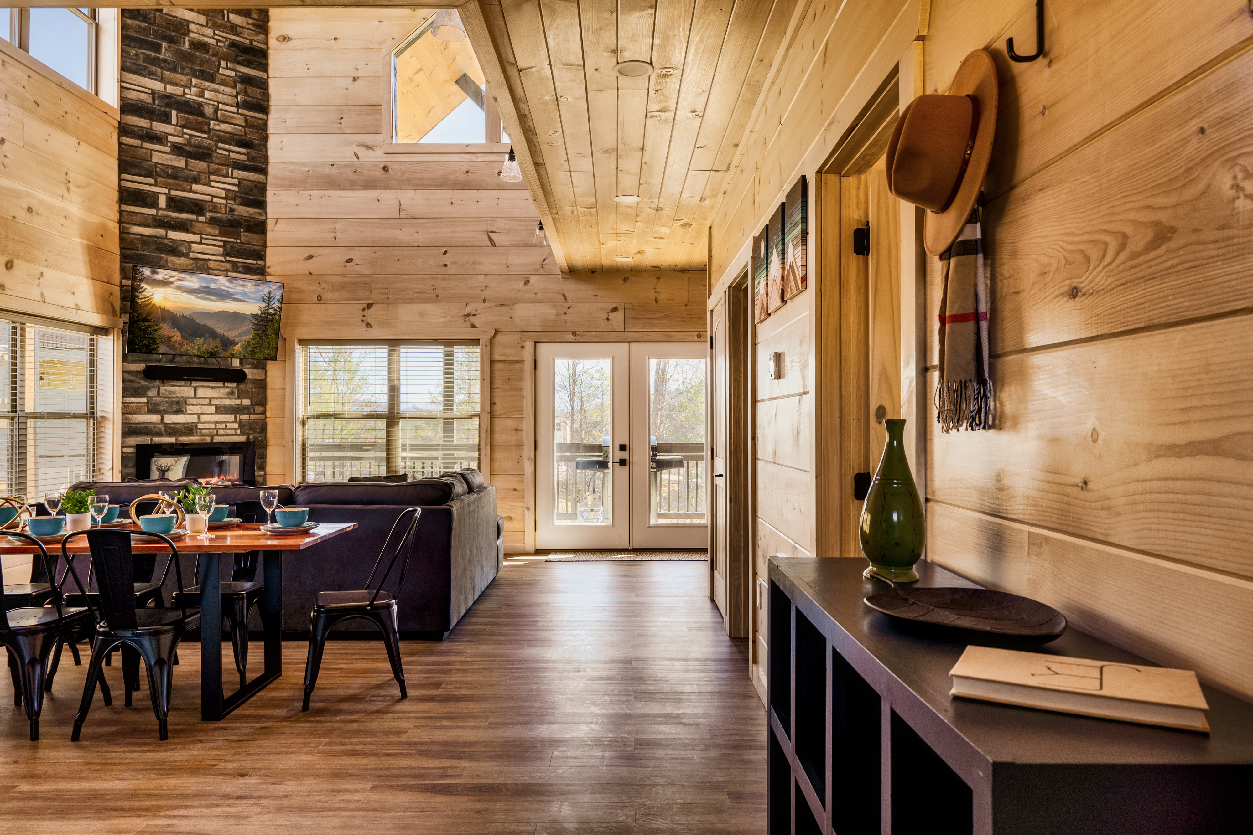 Cozy rustic cabin with stone fireplace, vaulted ceilings, and deck access