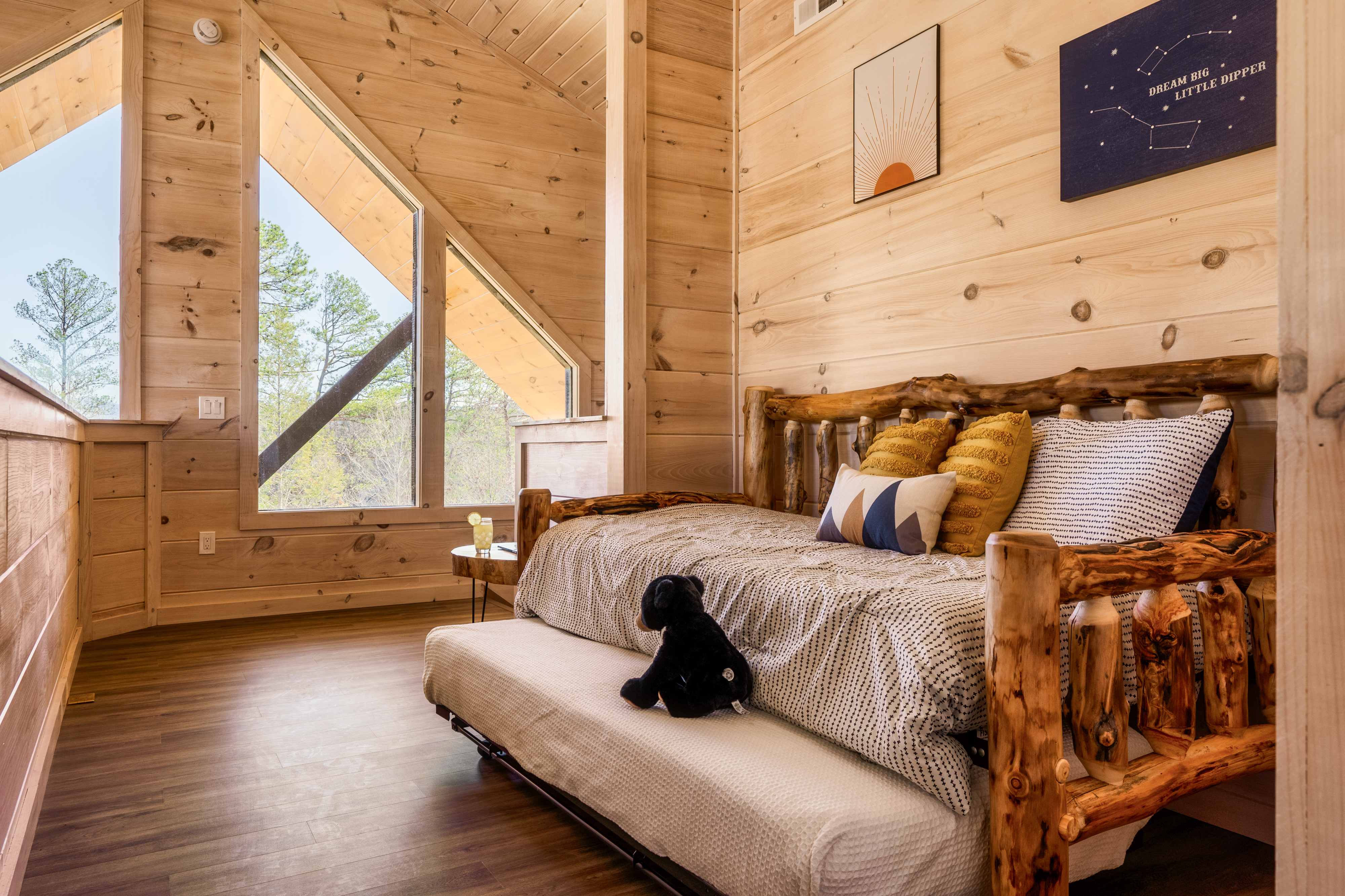 Cozy loft bedroom with rustic log bed and stunning woodland views