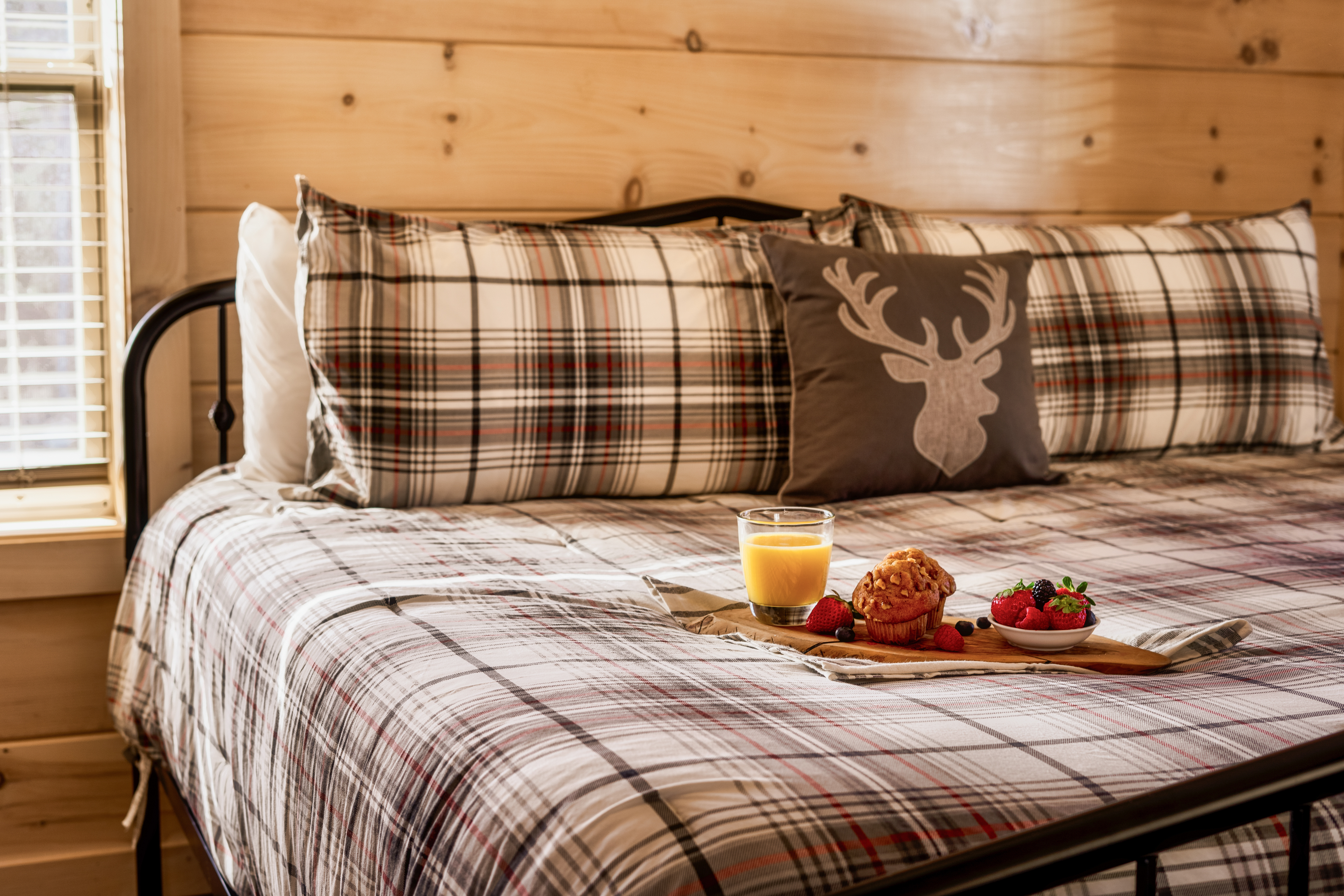 Cozy cabin-style bedroom with plaid bedding and breakfast in bed
