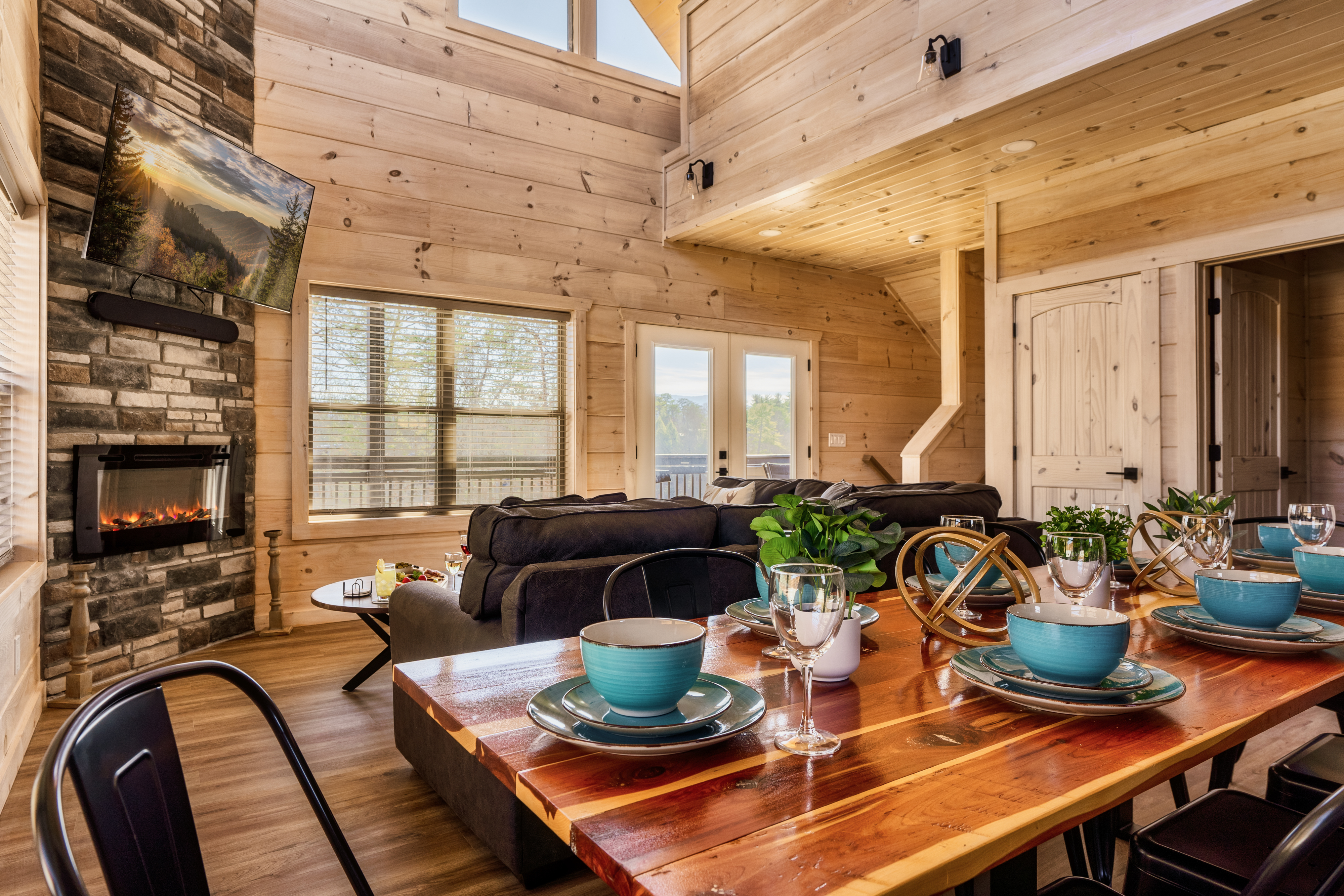 Cozy wood cabin great room with stone fireplace and stylish dining area