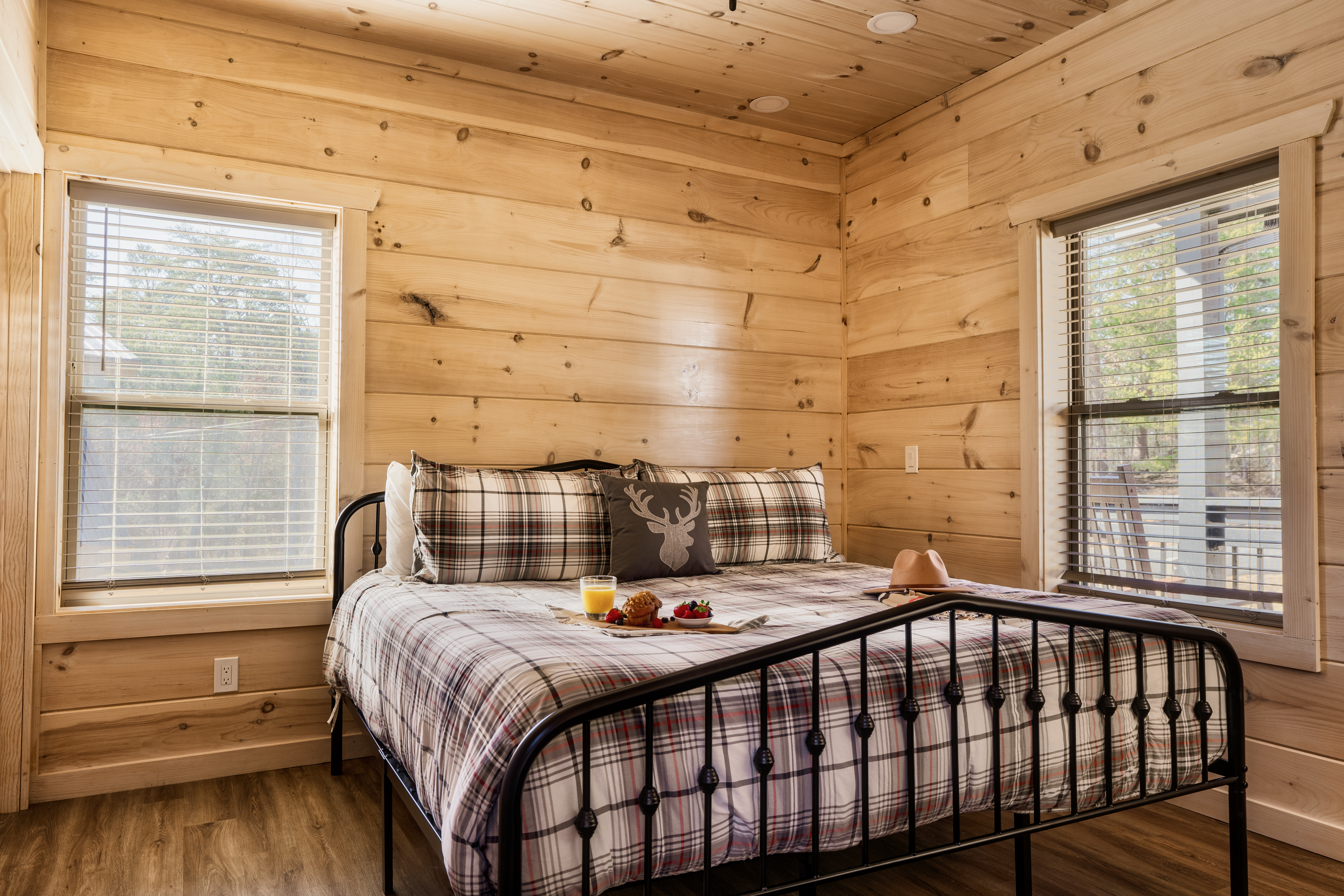 Cozy cabin bedroom with plaid bedding and sunlit woodland views
