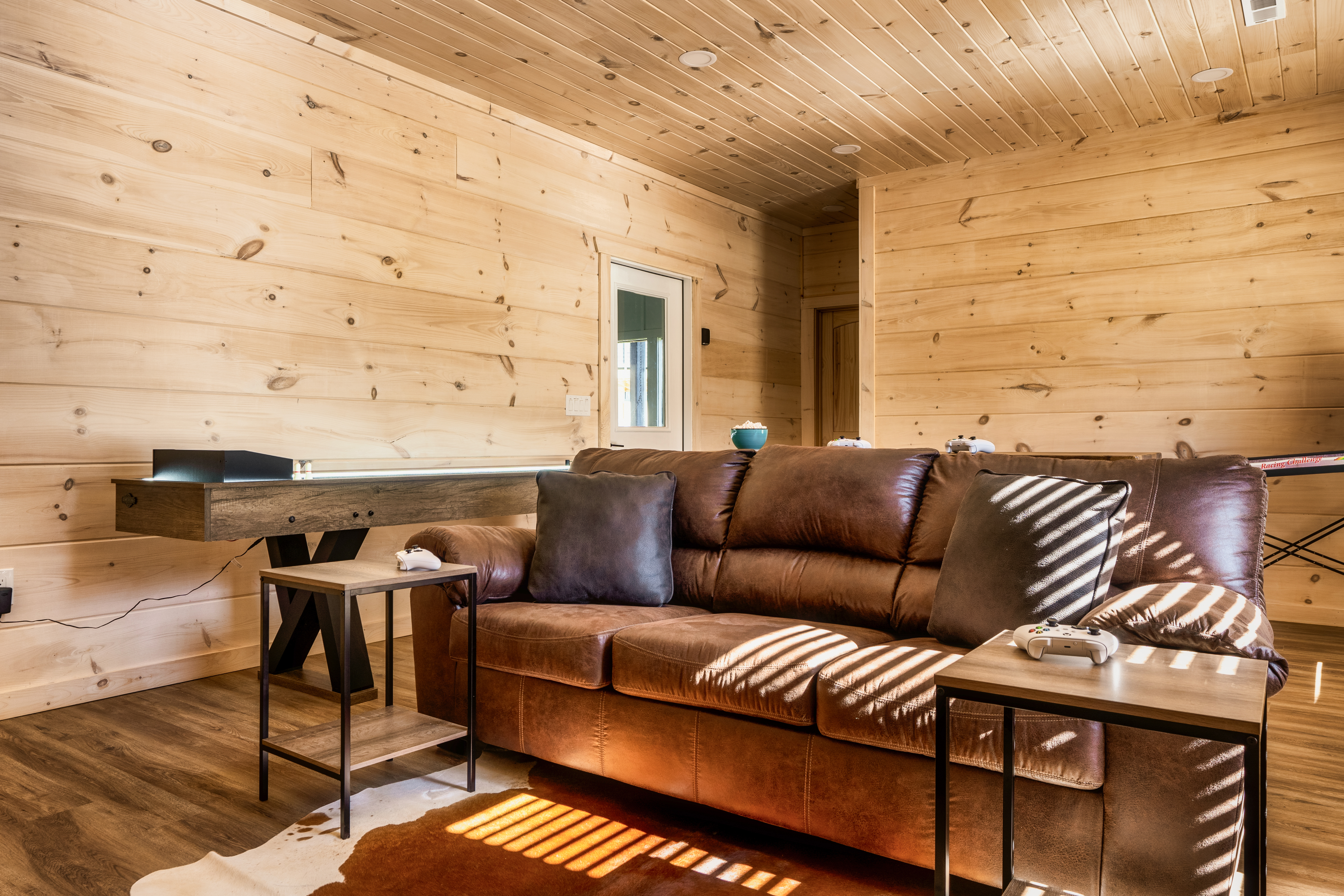 Cozy wood-lined lounge with leather sofa and fun game table