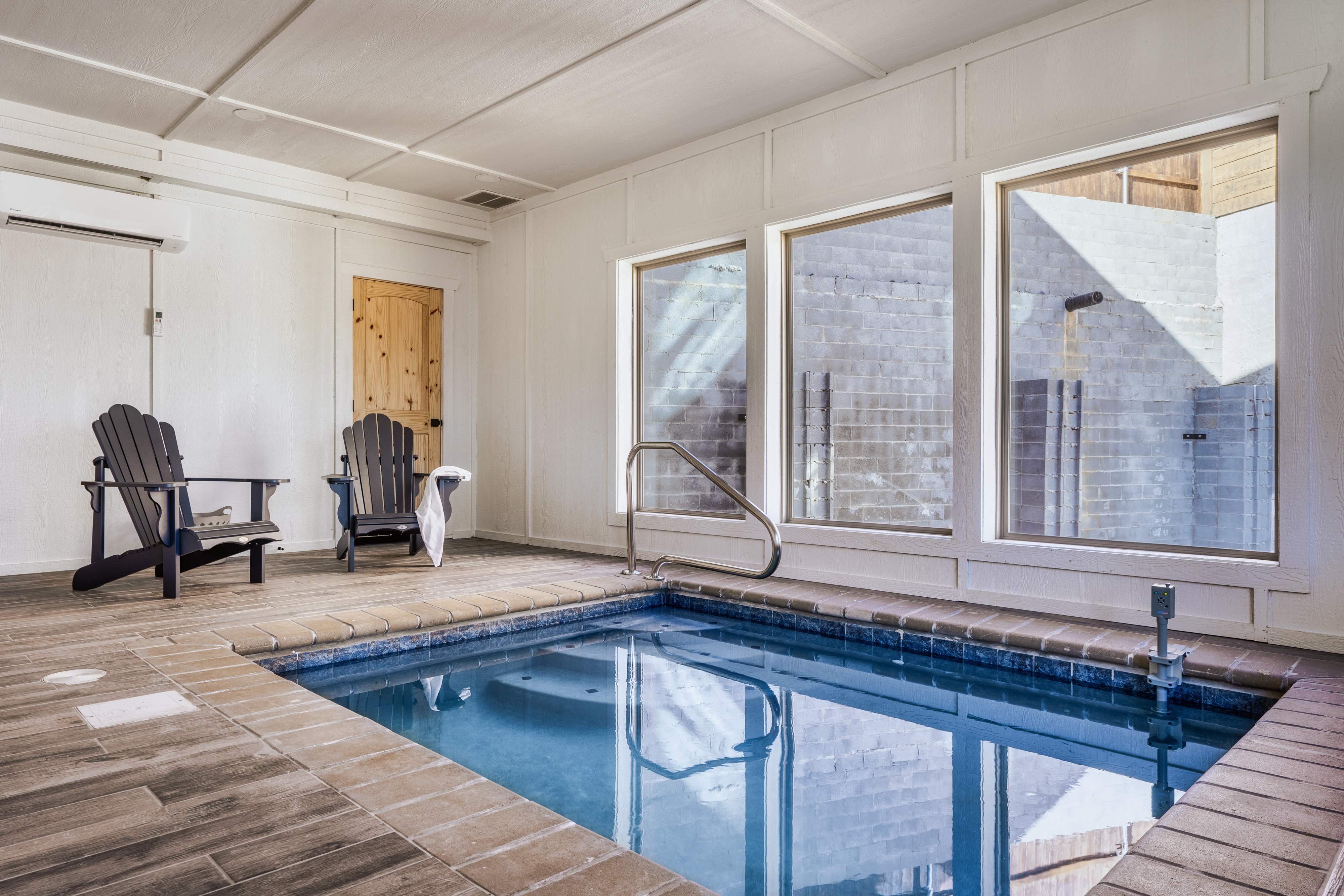 Private indoor plunge pool with natural light and cozy lounge seating