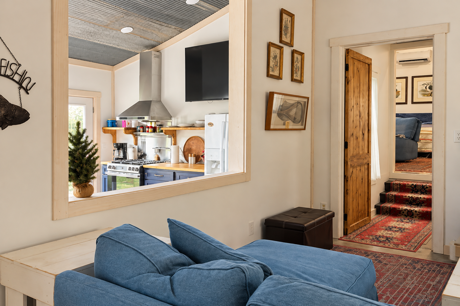 Cozy lounge with blue sectional, character rugs, and peek-through kitchen