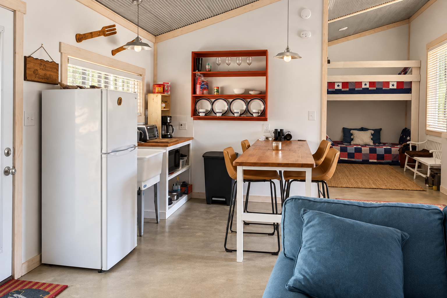 Open-plan cabin kitchen and dining area, with the connected triple-bunk nook containing three twin mattresses.