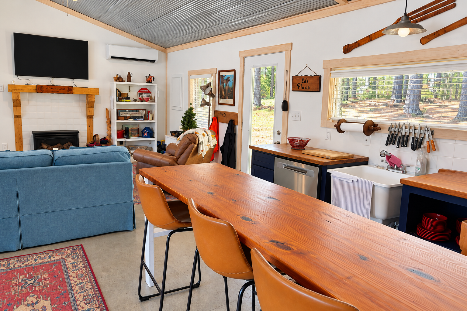 Cozy cabin great room with fireplace, rustic dining table, and forest views