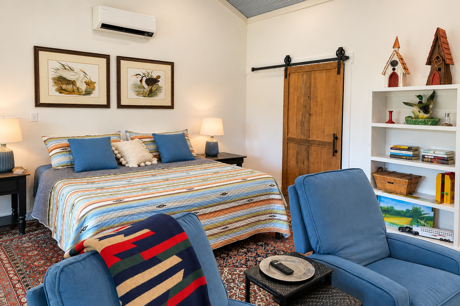 Cozy king bedroom with barn door, lounge chairs, and stylish rustic charm