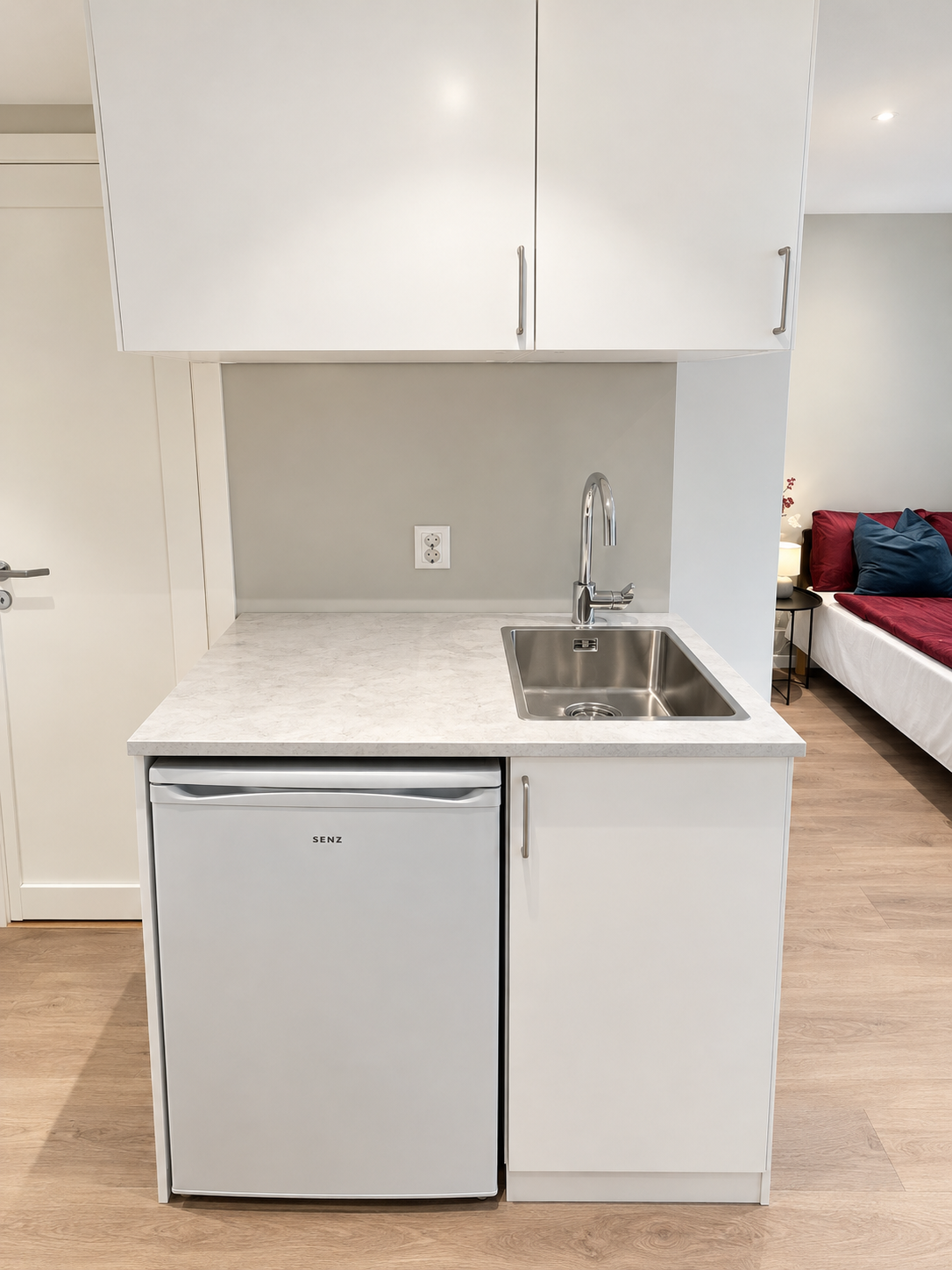 Modern compact kitchenette with mini fridge and sleek sink setup