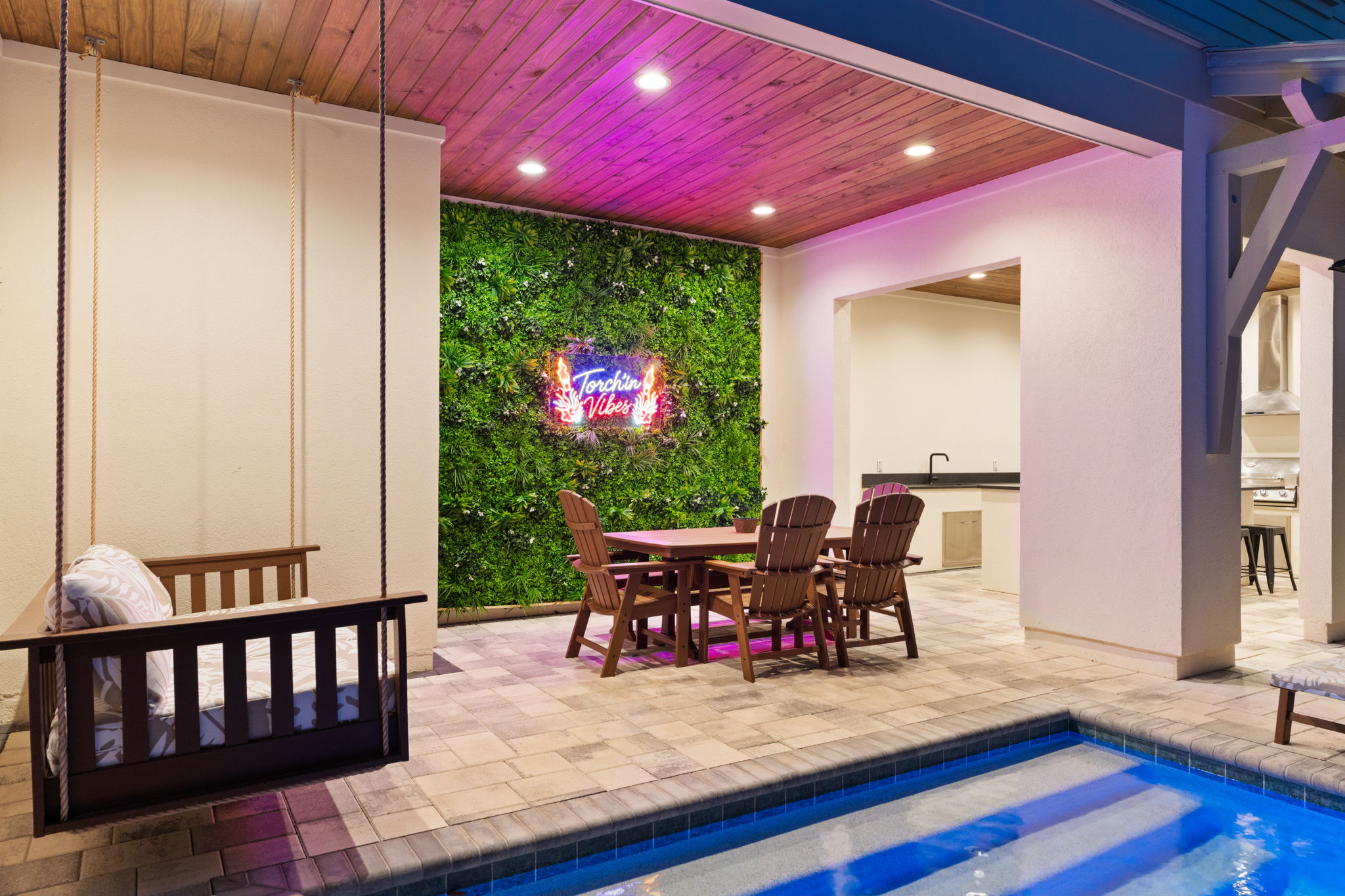 Stylish patio with plunge pool, swing, and chic neon accent wall