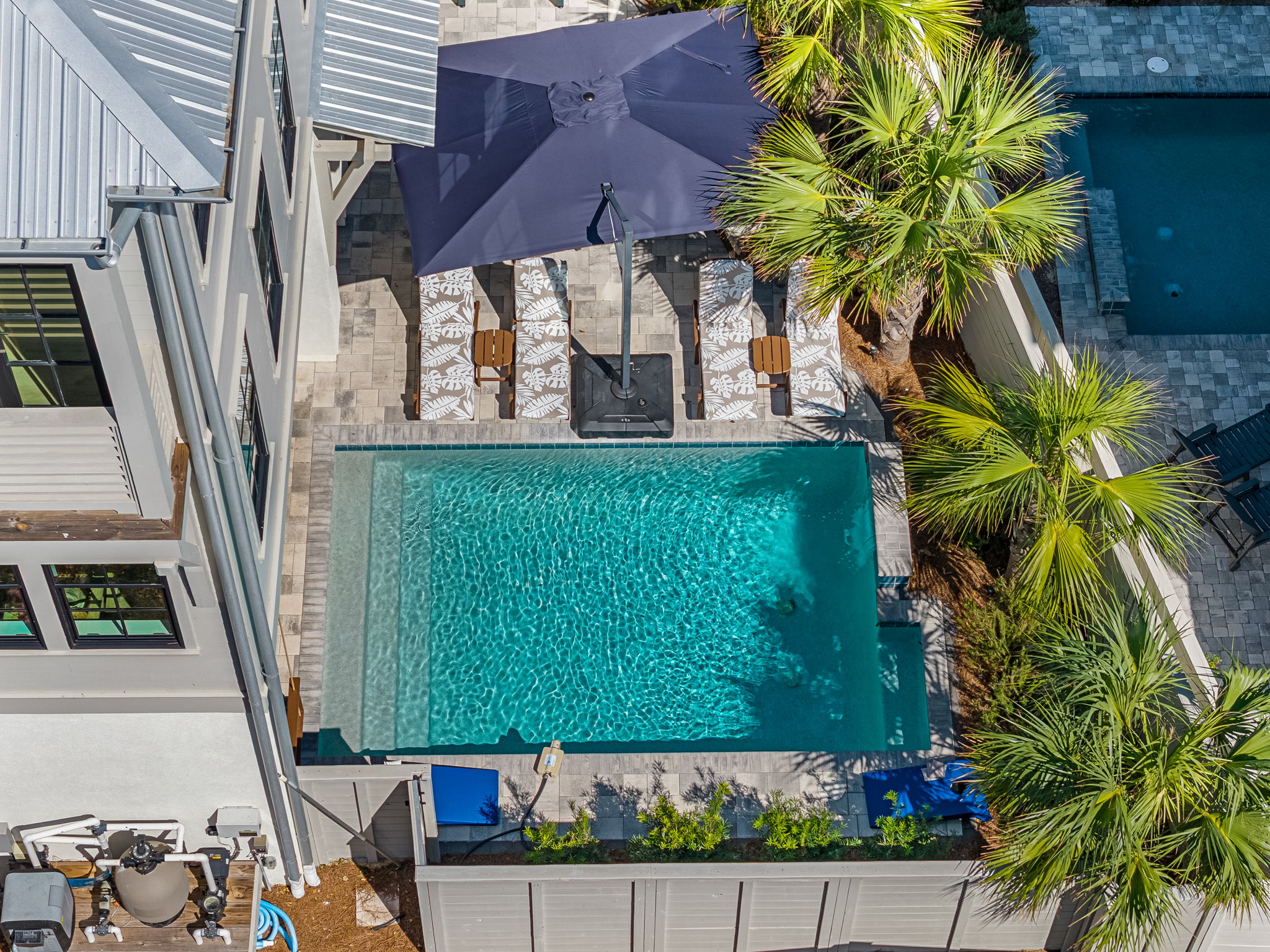 Private pool oasis with loungers, shade umbrella, and tropical palms