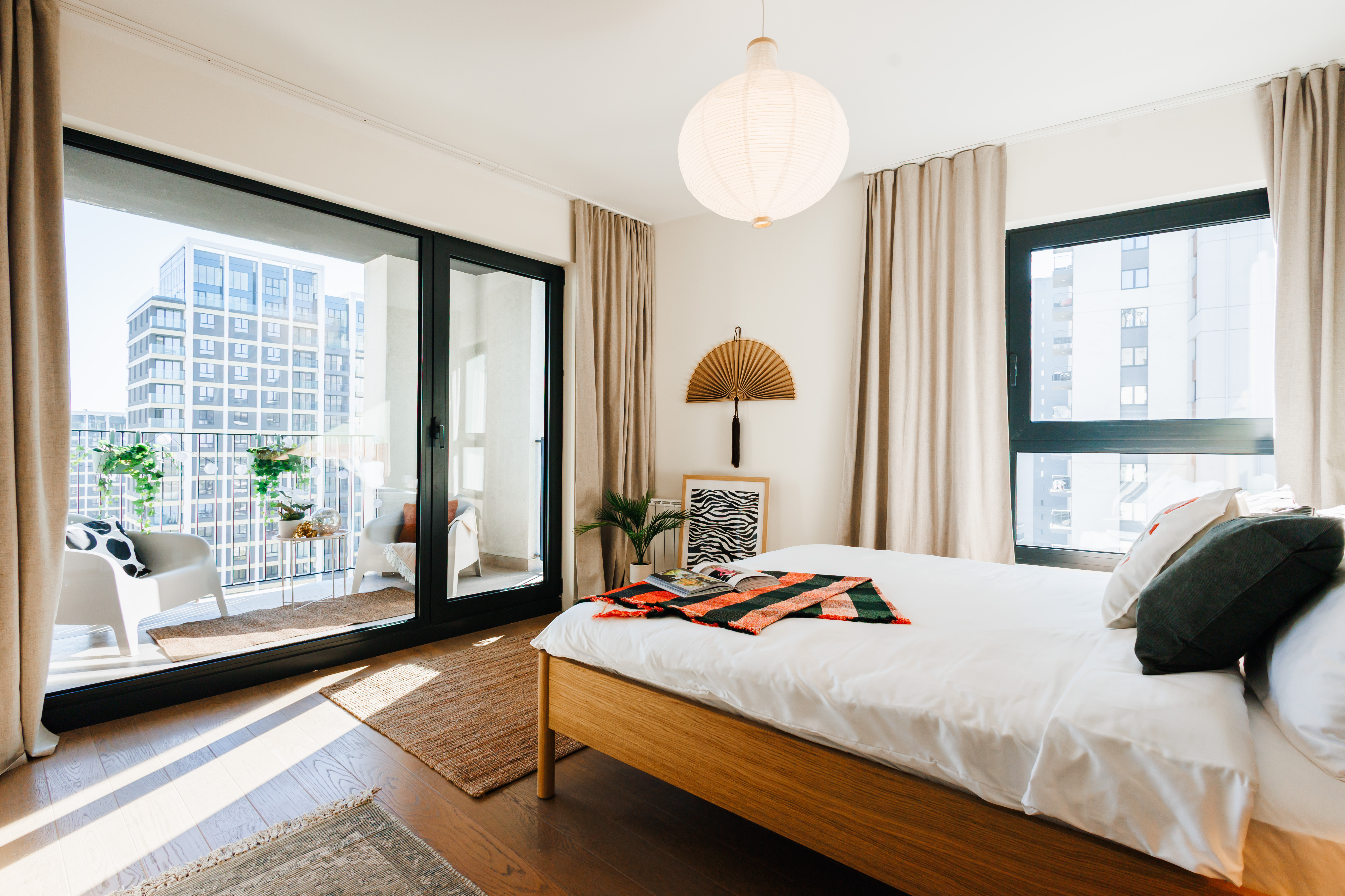 Sunlit bedroom with private balcony seating and stylish city views