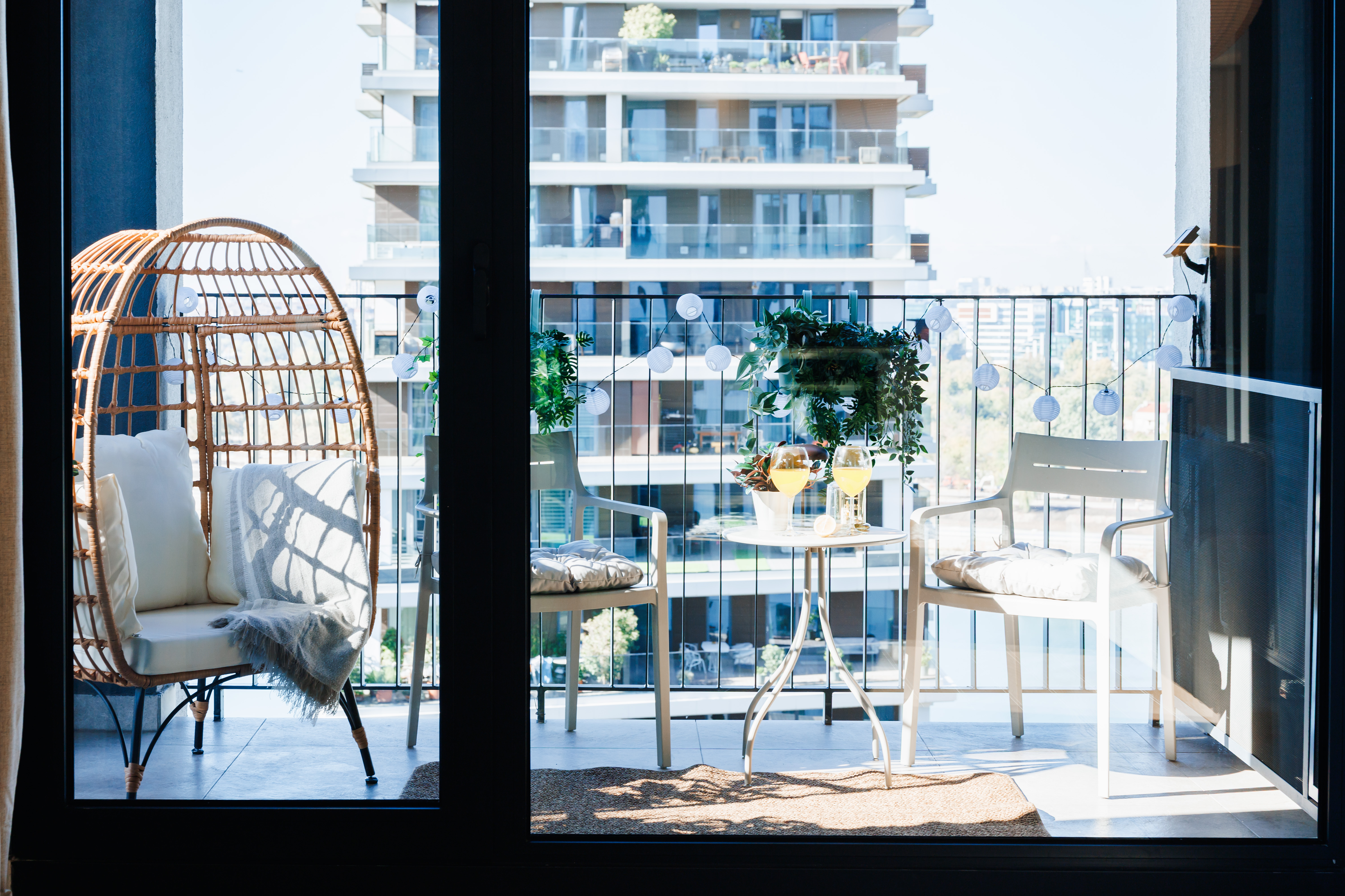 Sunny private balcony with egg chair, cozy seating, and city views