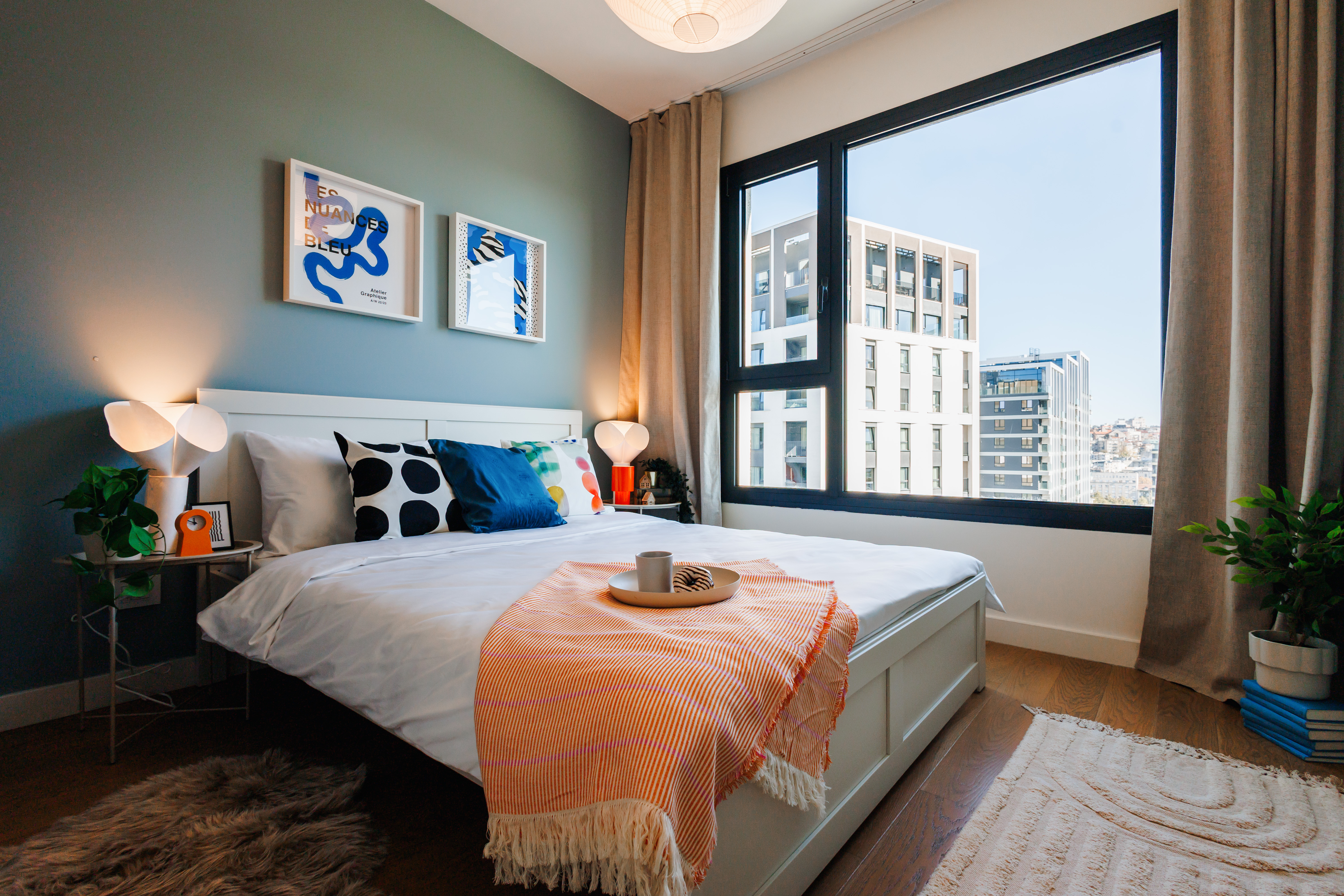 Bright modern bedroom with city views and cozy designer touches