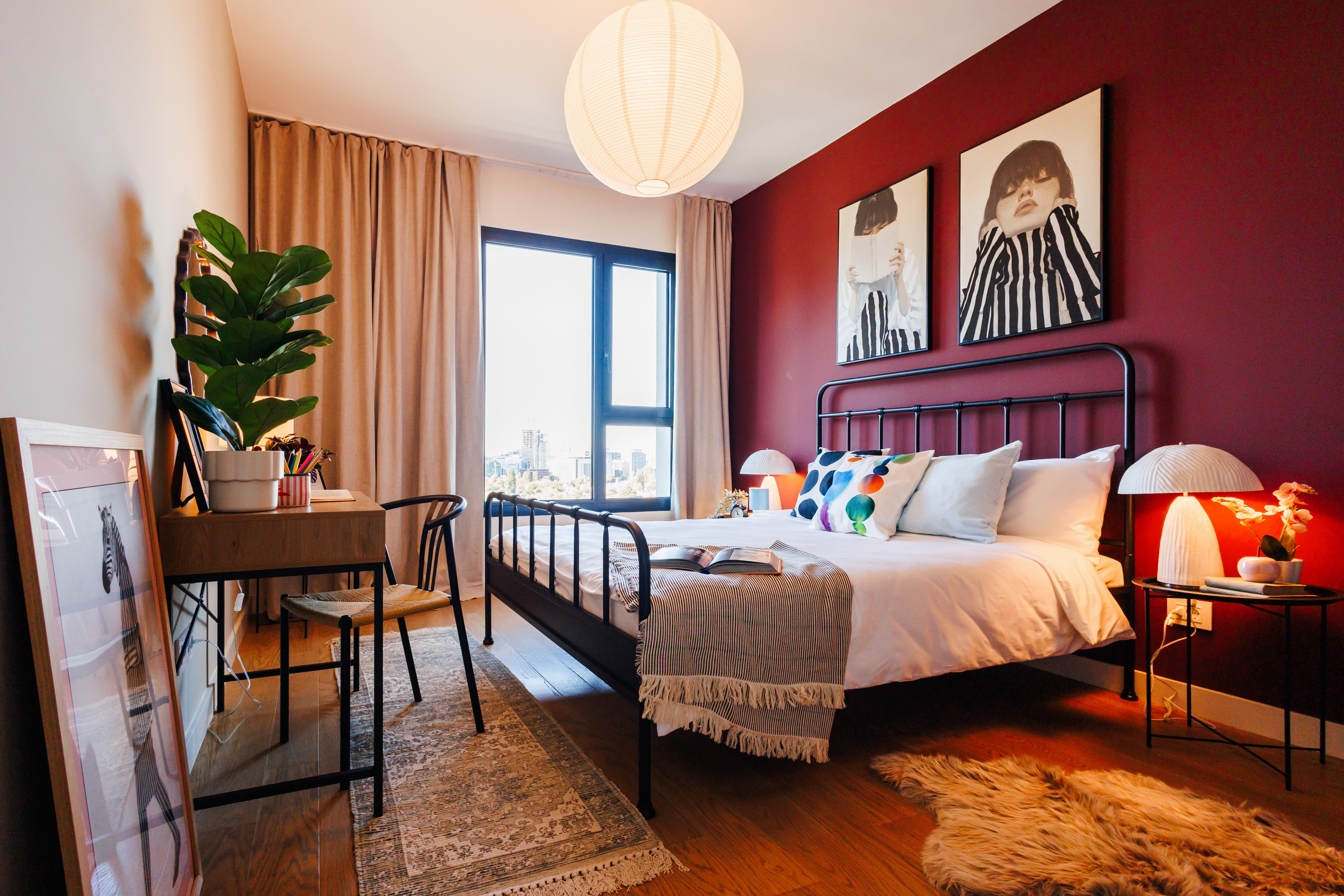 Stylish sunlit bedroom with desk, bold decor, and cozy boutique charm