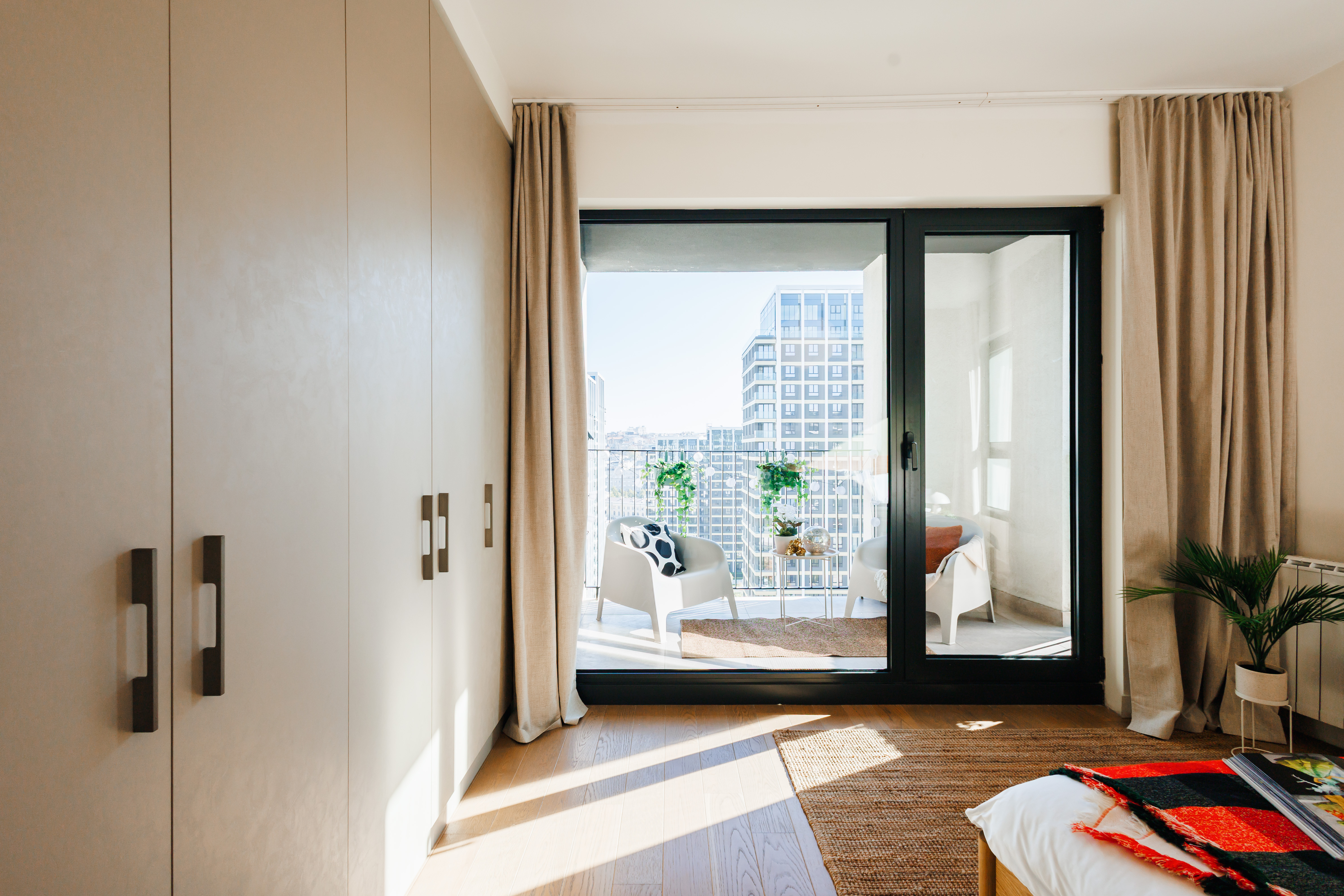 Sunlit bedroom with private balcony seating and stylish city views
