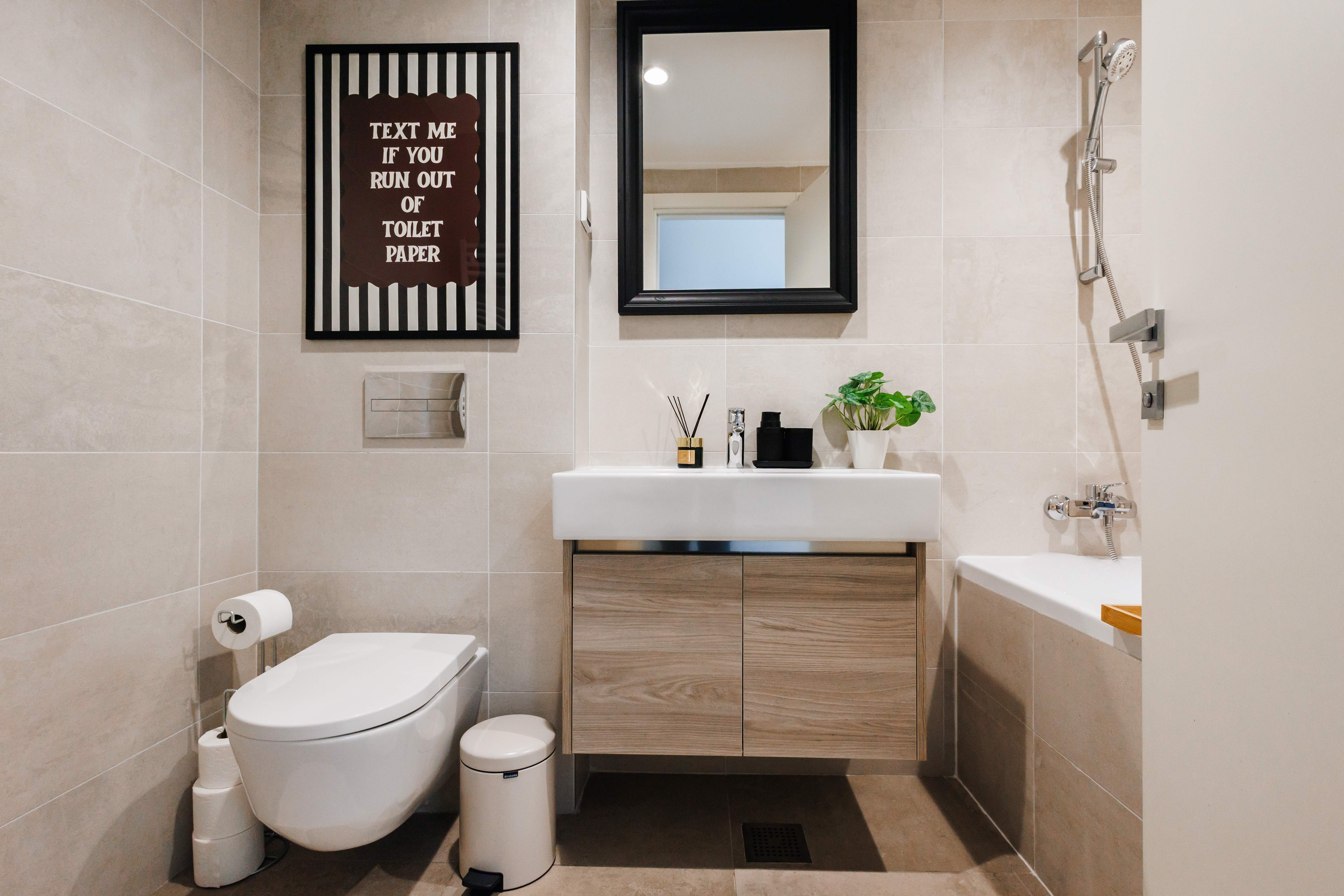 Modern tiled bathroom with sleek vanity, tub shower, and stylish touches