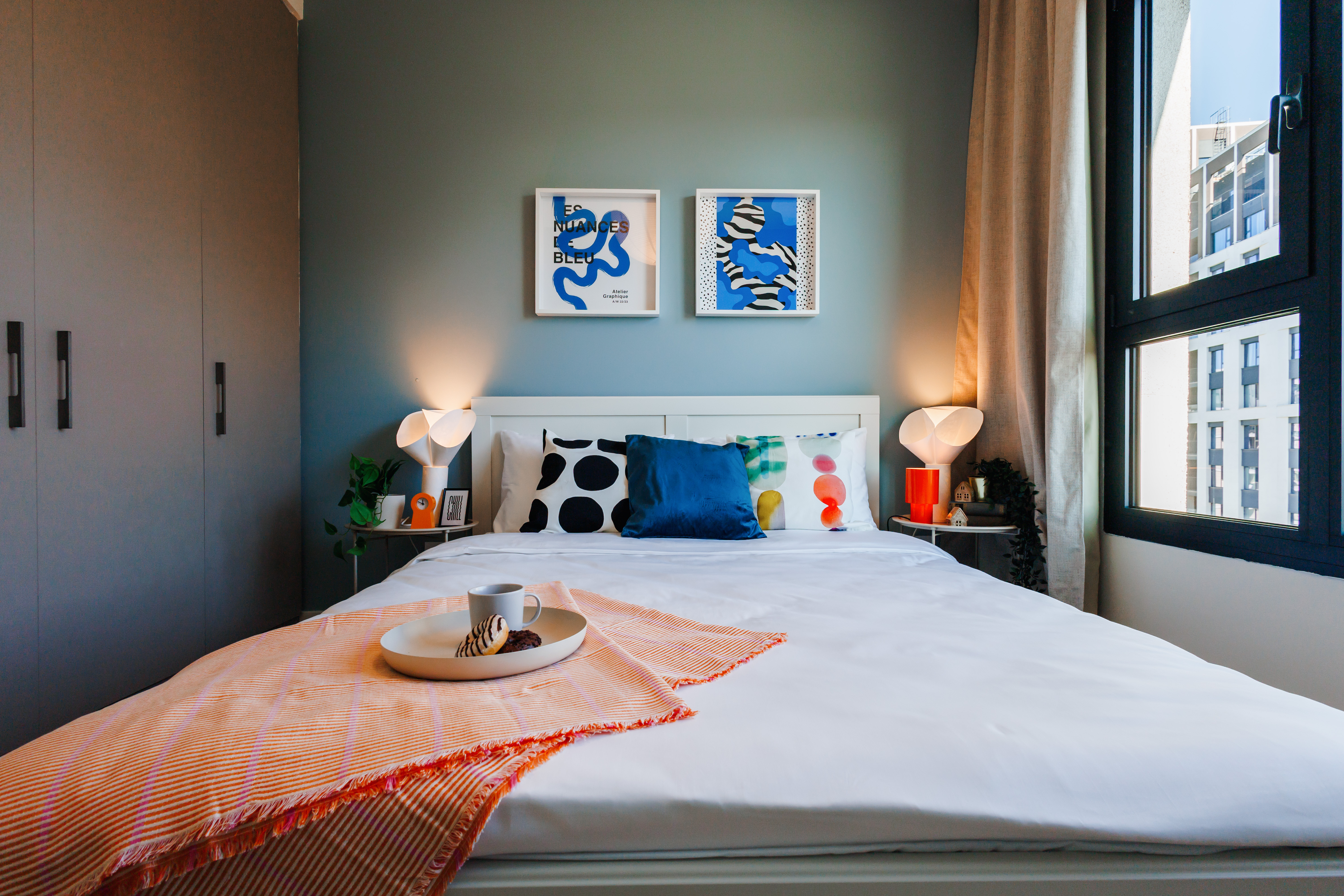 Bright modern bedroom with city views, sleek storage, and cozy styling