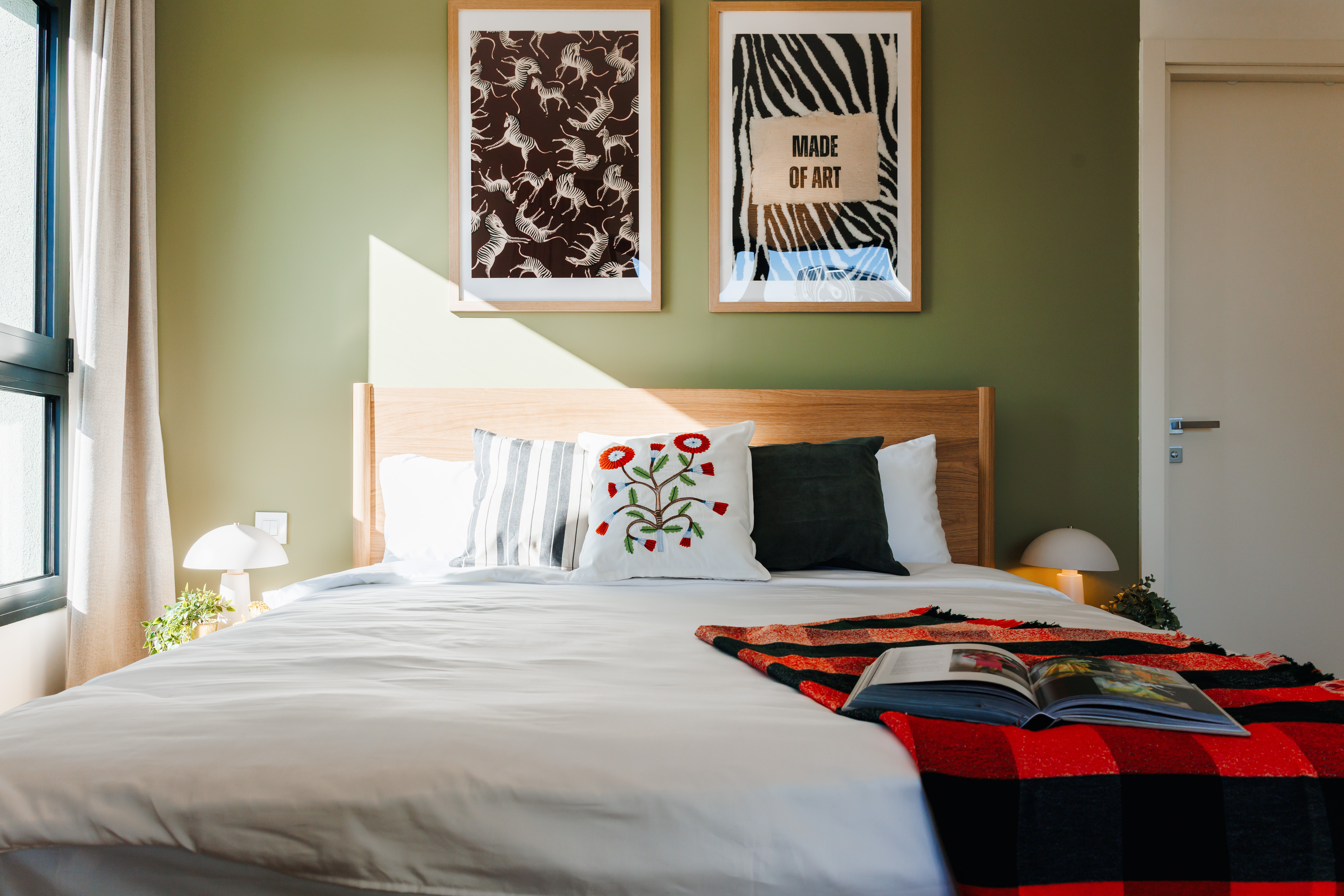 Bright, artful bedroom with cozy linens and warm natural light