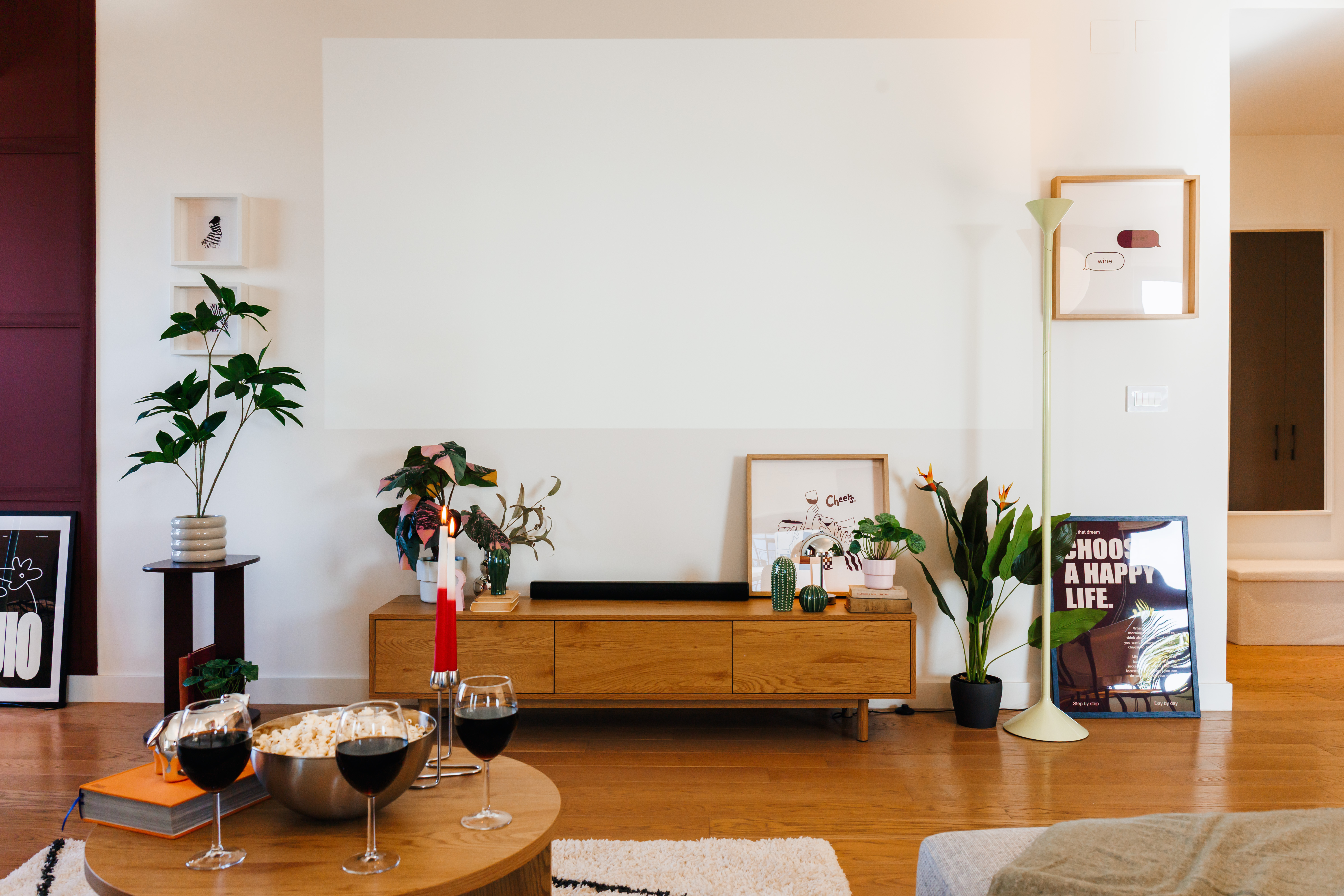 Bright modern living room with stylish decor, plants, and cozy wine setup