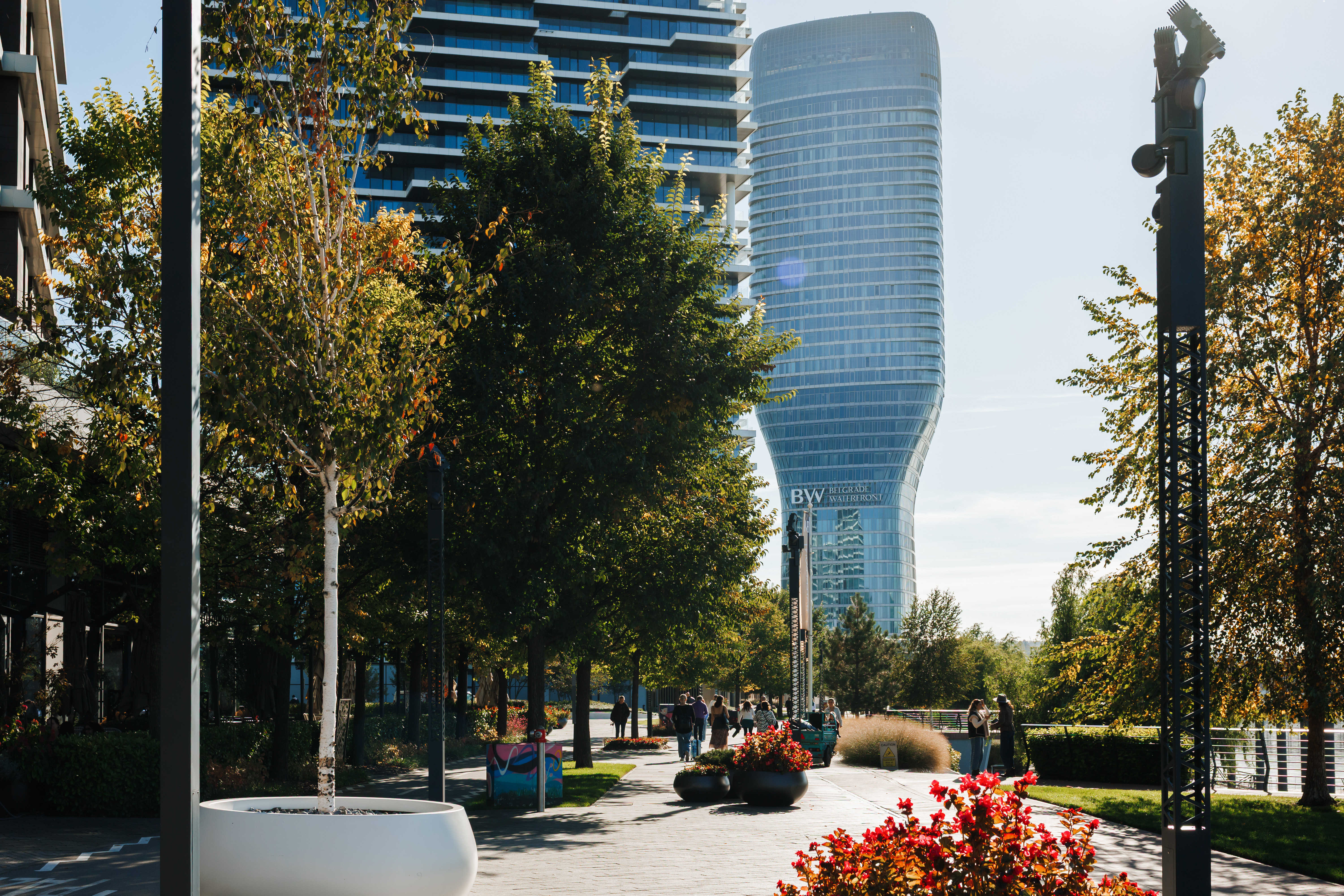 Tree-lined urban promenade with landscaped paths and modern skyline views