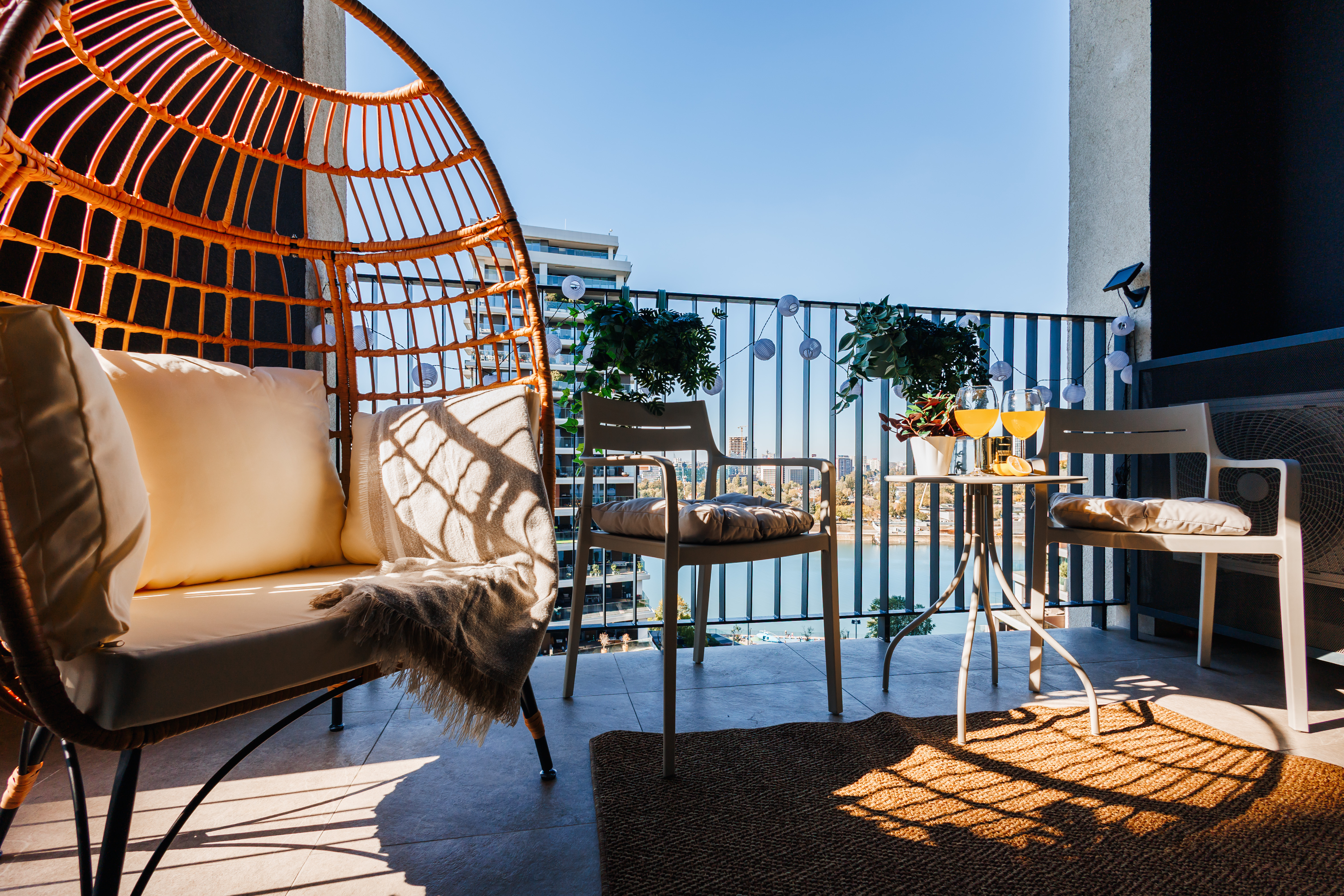 Sunny balcony with egg chair, water views, and cozy outdoor seating