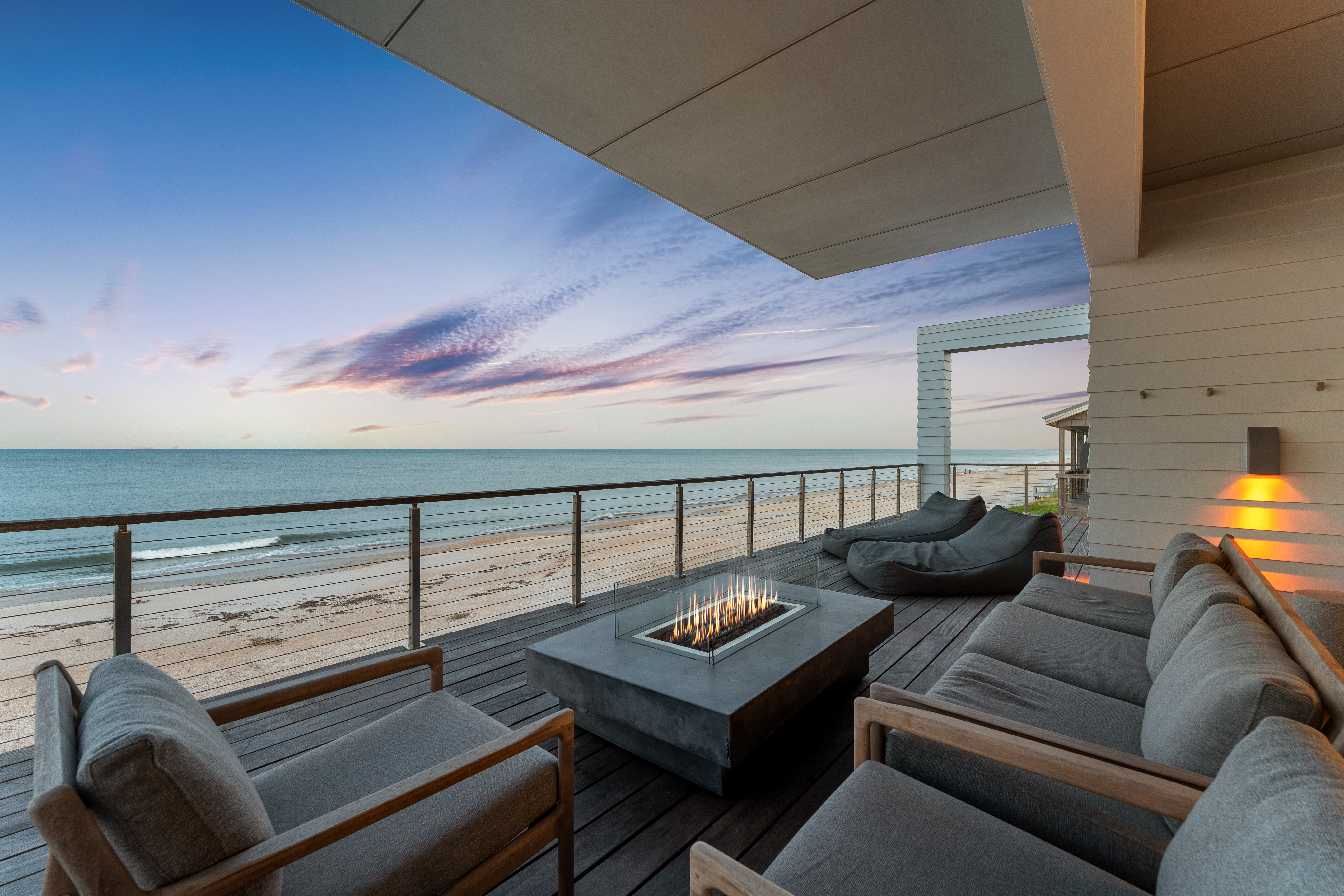 Oceanfront sunset deck with cozy lounge seating and a modern fire table