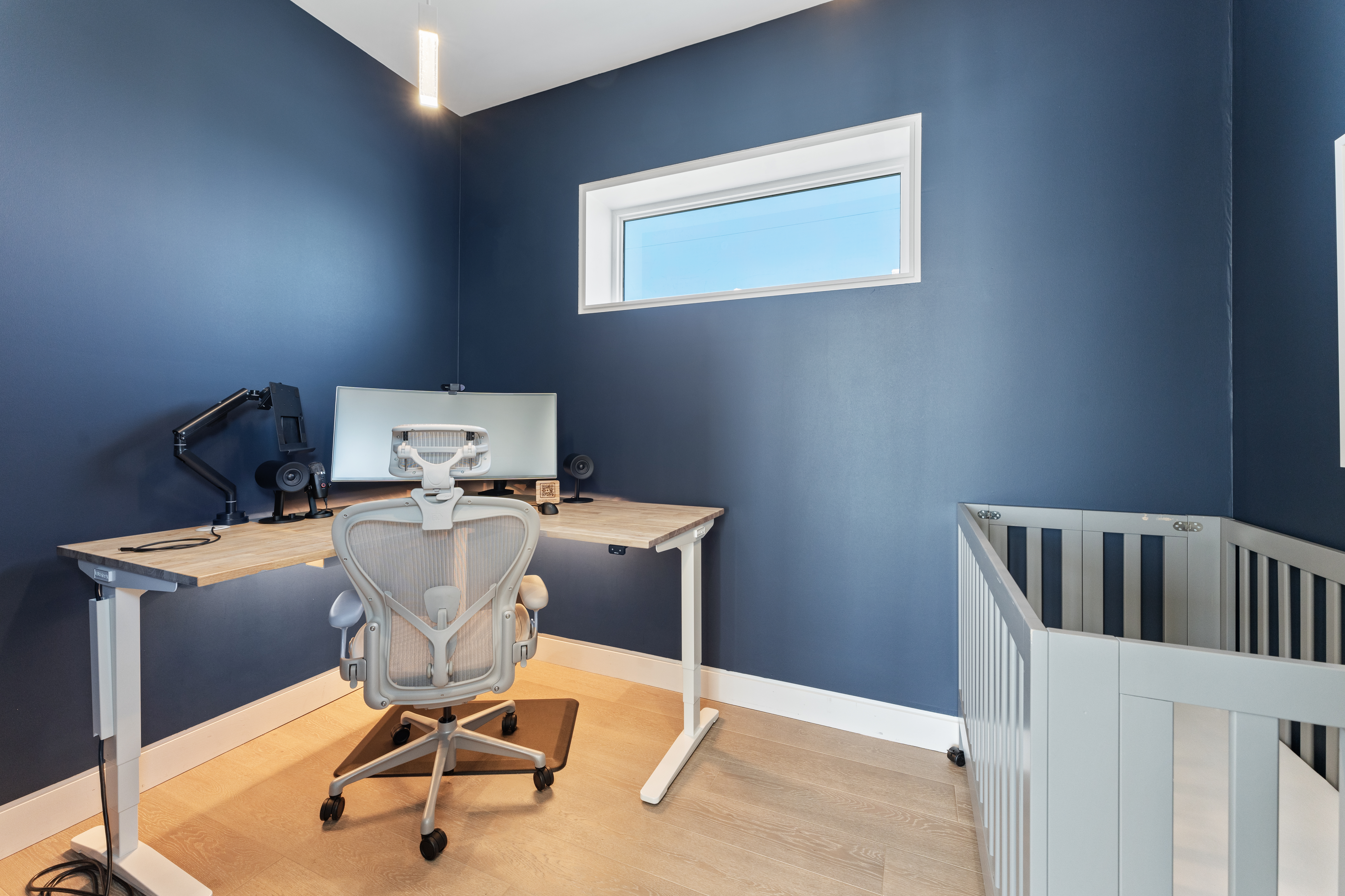 Modern home office with sit-stand desk and crib for family-friendly stays