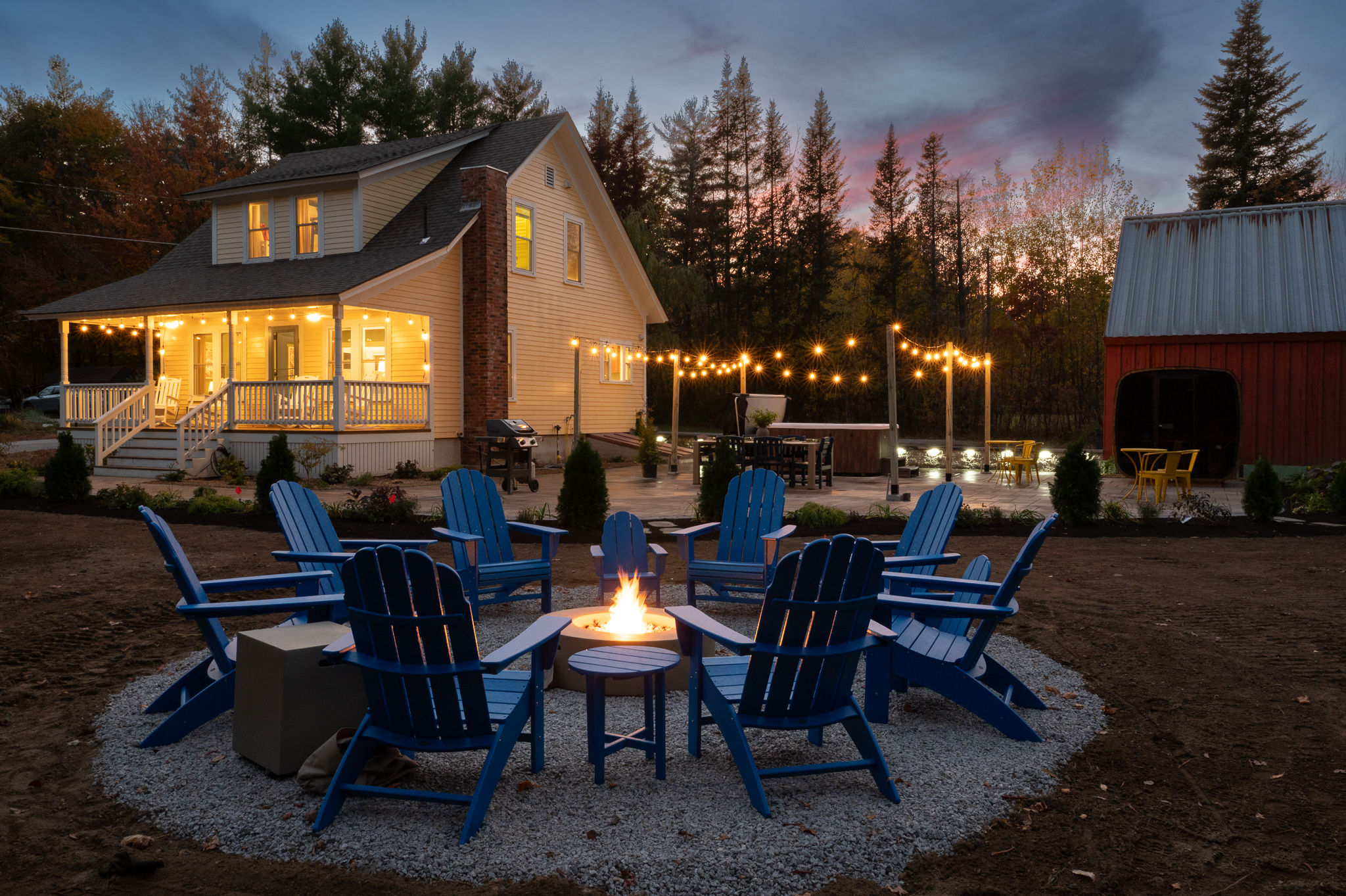 Cozy fire pit, hot tub, and string-lit backyard at sunset