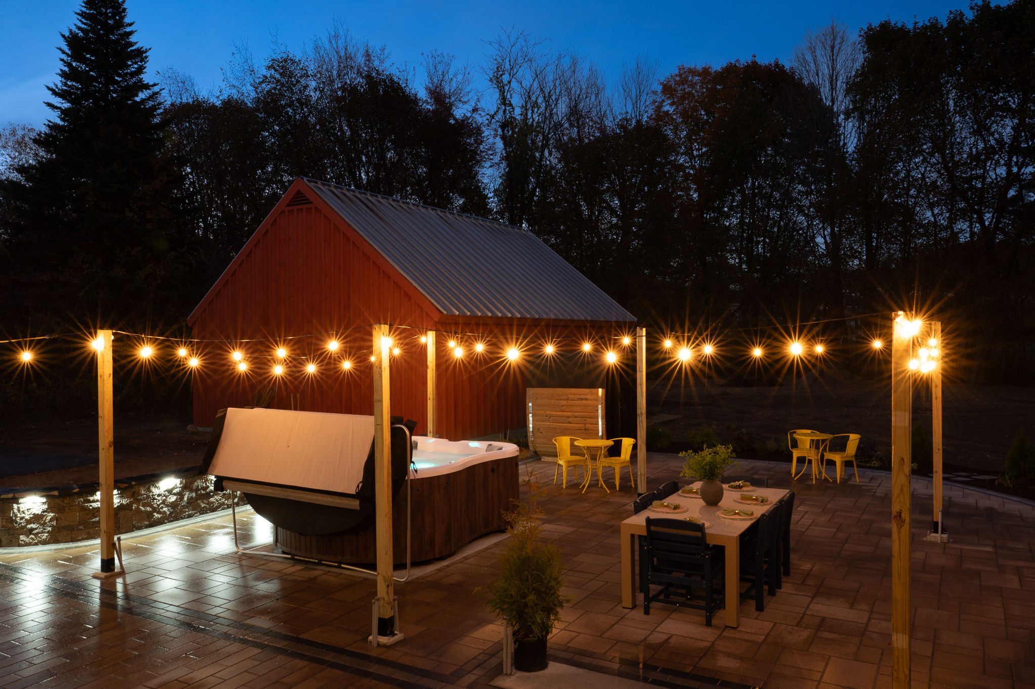 Cozy lit patio with hot tub, outdoor dining, and private woodland charm