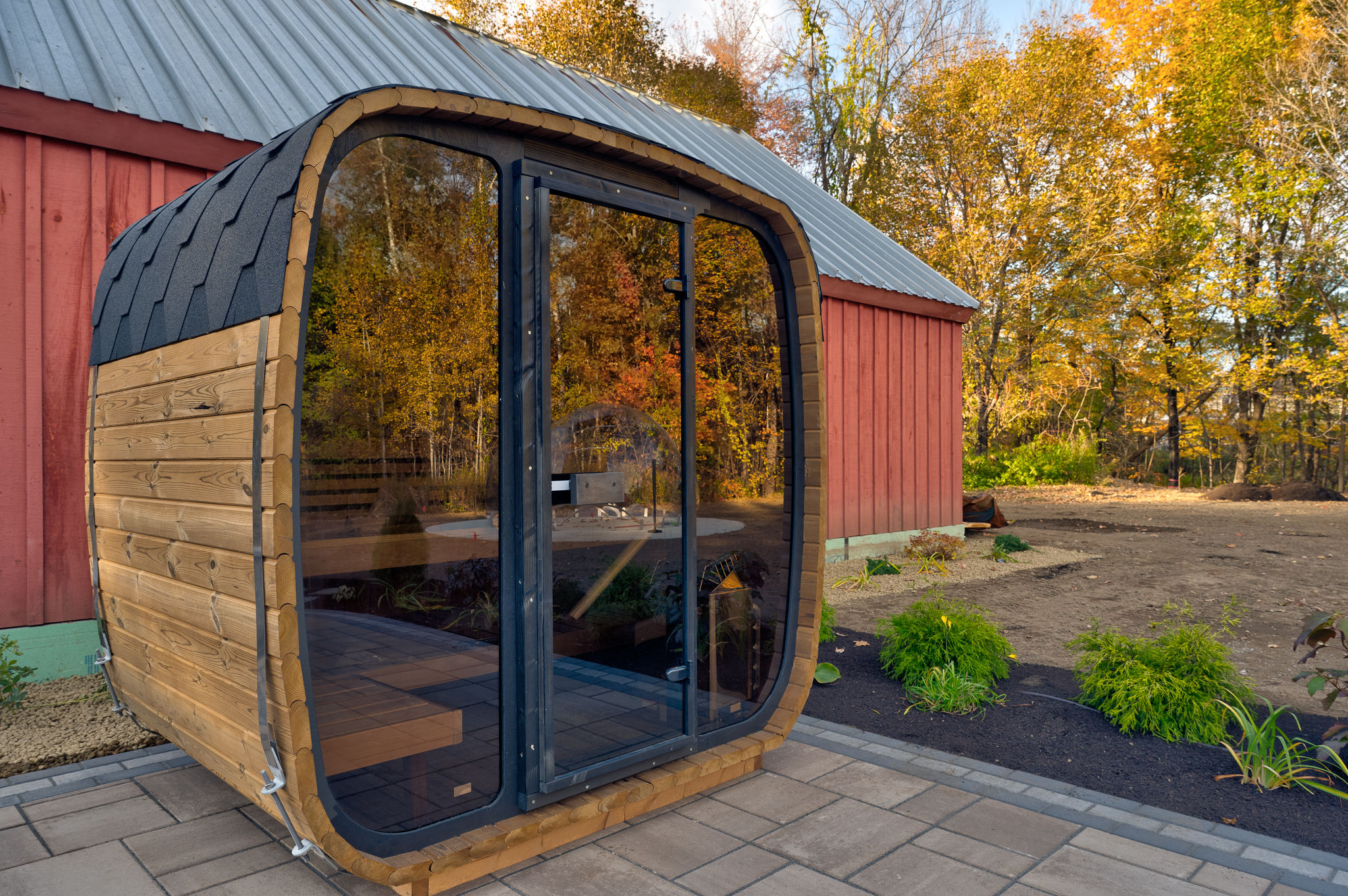 Private outdoor sauna with sleek glass front and serene autumn setting